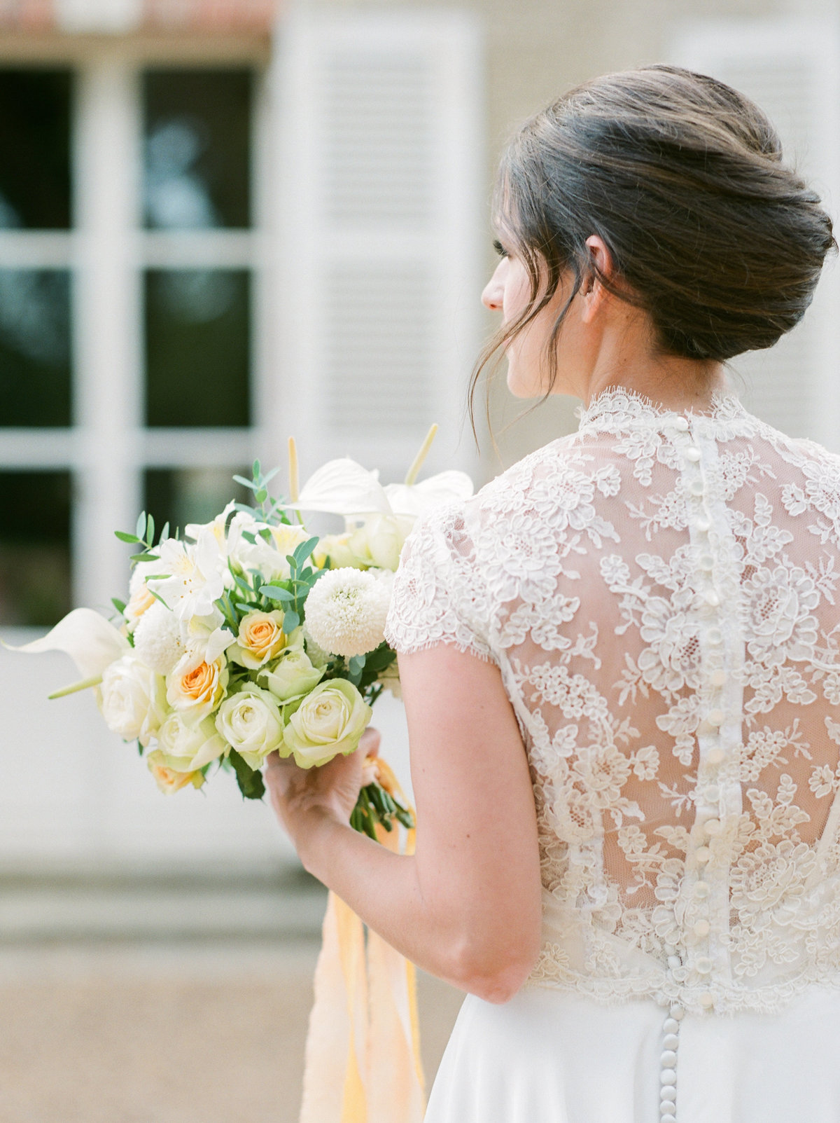 bride in short sleeve lace dress holding bouquet looking away from camera