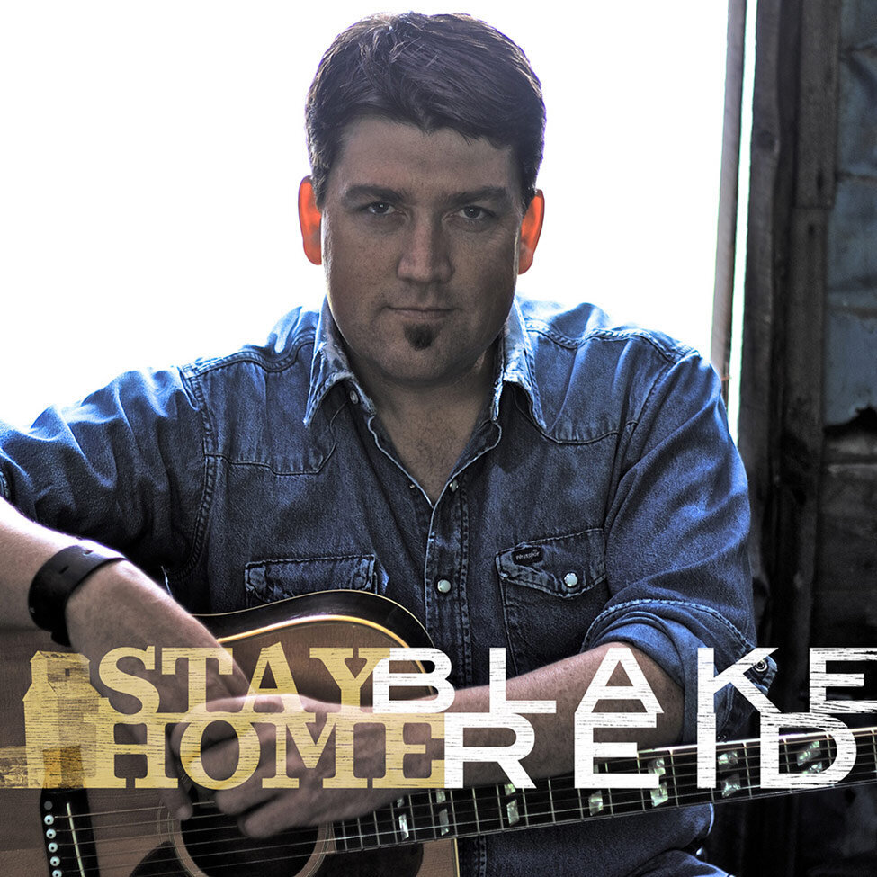 Single Cover Title Stay Home Artist Blake Reid sitting in doorway white light behind him guitar in his lap
