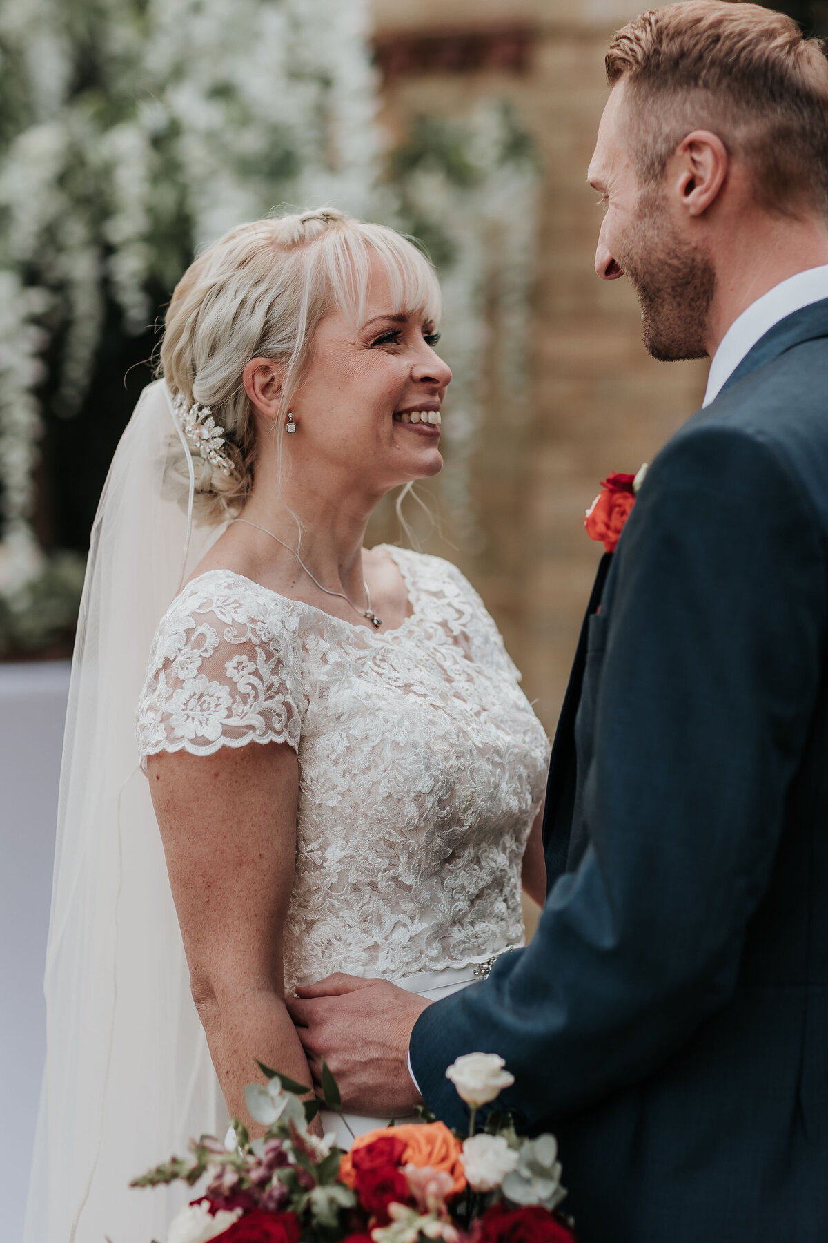 Bride smiles at her Groom wearing stunning lace dress at their Autumn wedding at The Ravenswood