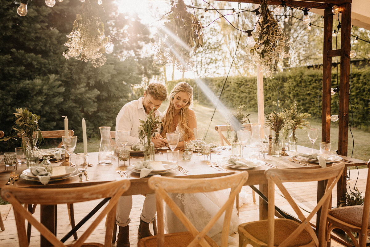 Brautpaar an Tisch im Sonnenschein
