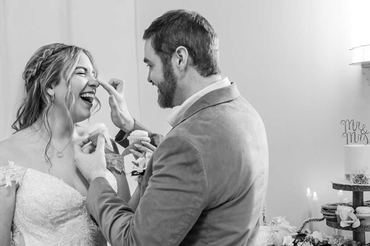 A married couple sharing cupcakes at their wedding reception by JoLynn Photography, a Raleigh wedding photographer