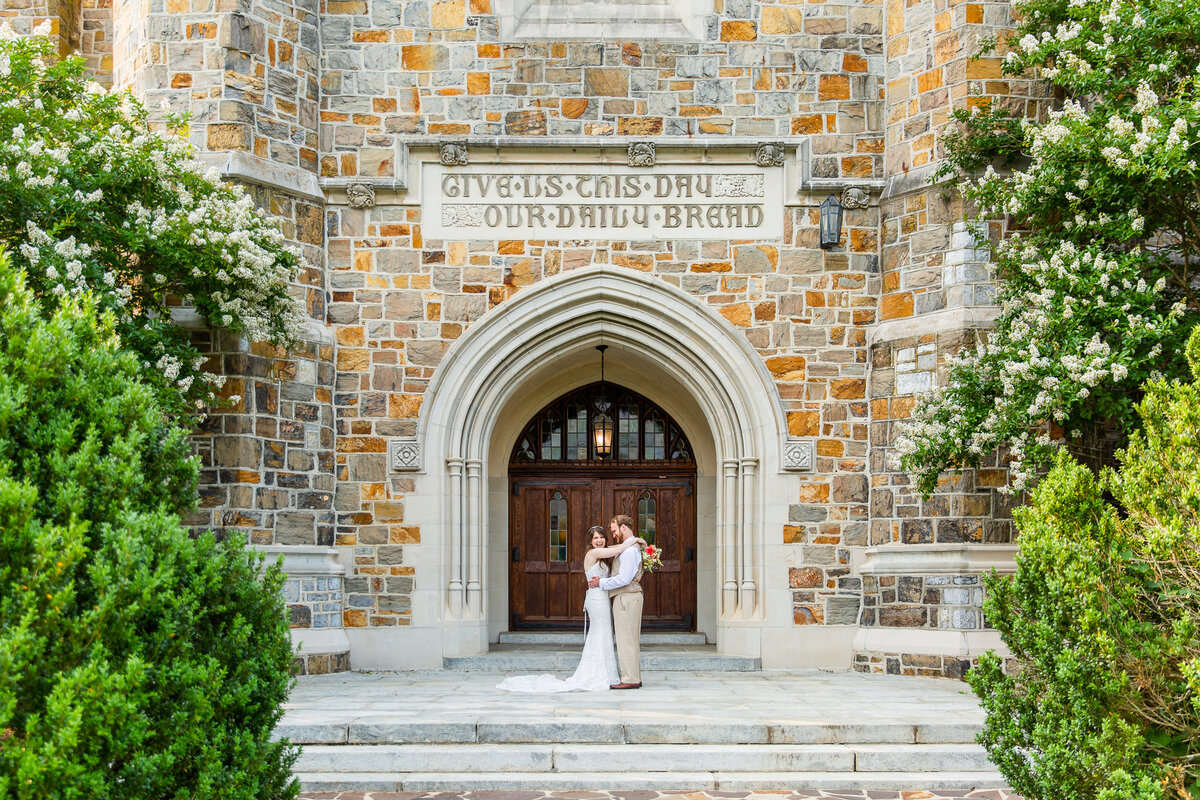 bride and groom kissing in front of a  stone church