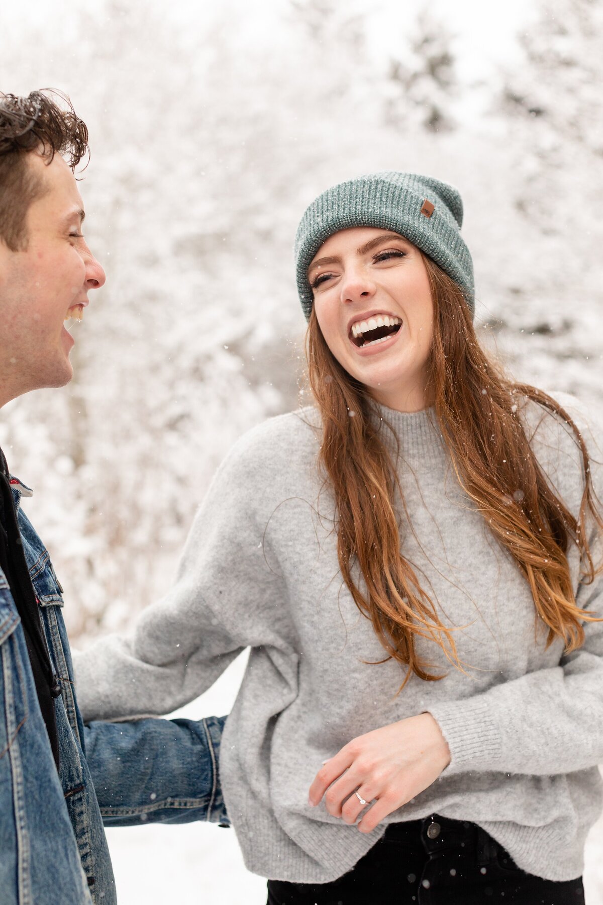 Casual-and-fashionable-couple-laughs-after-a-snow-fight-during-their-winter-engagement-session-at-Sydenham-ridge