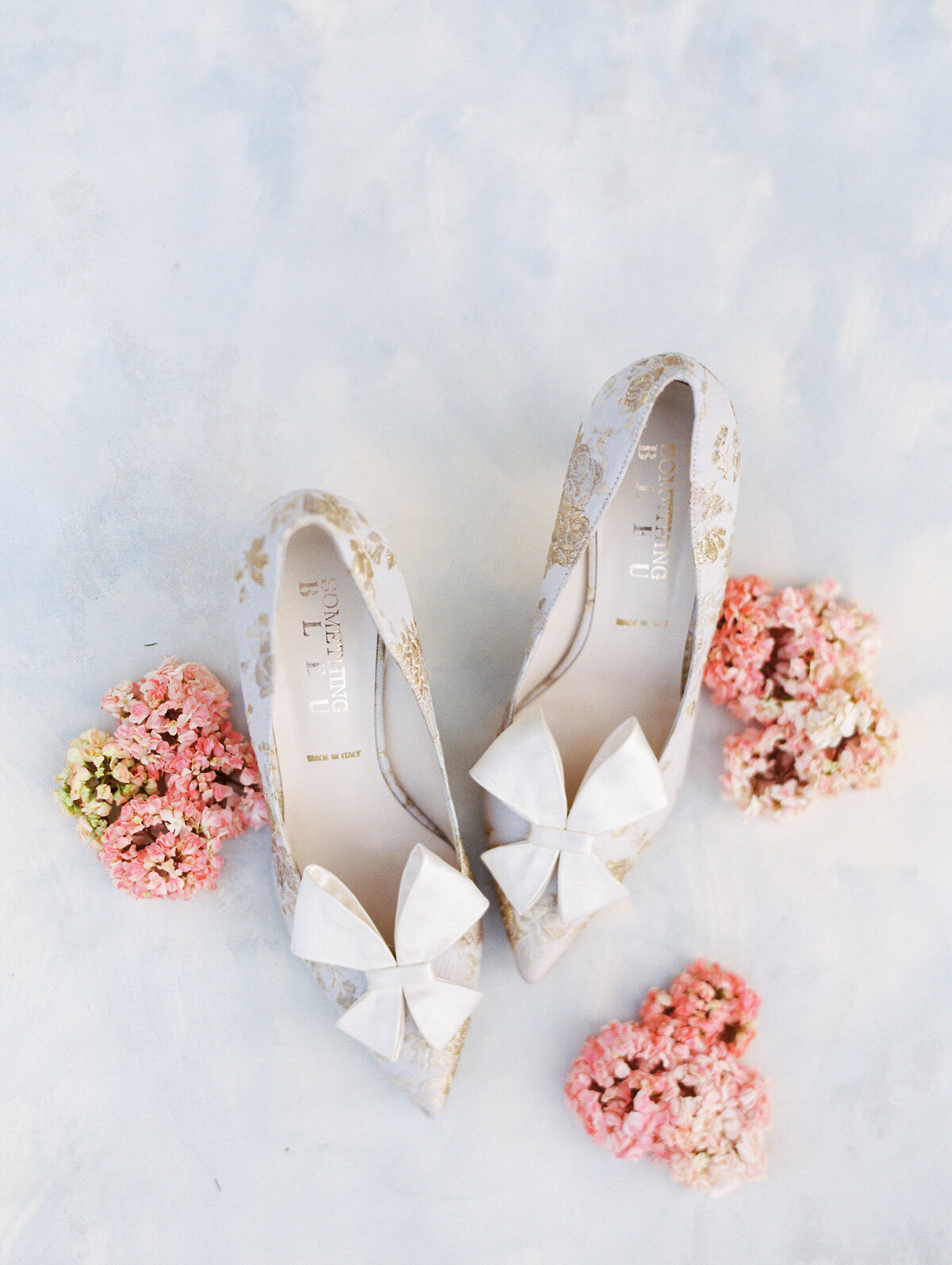 wedding shoes with pink flowers around them