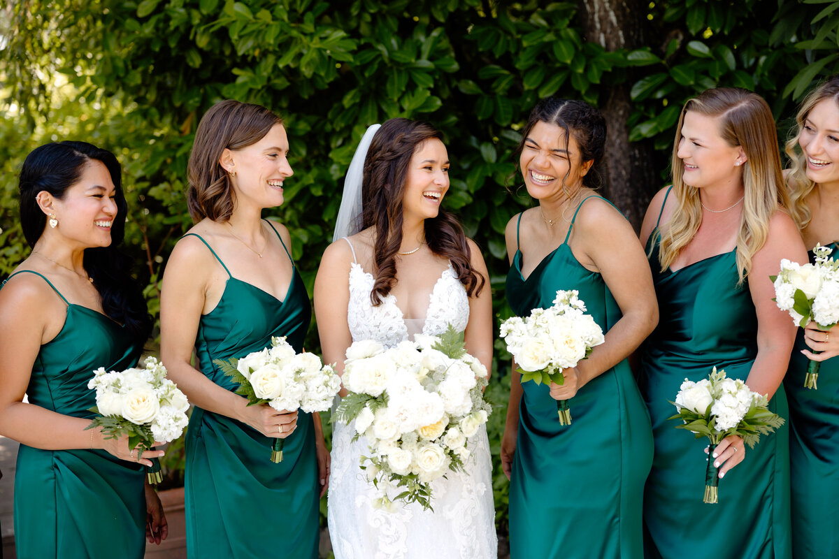 bride and bridesmaids hold white bouquets and laugh together at kiana lodge