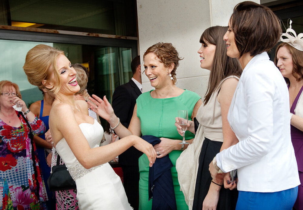 bride with beehive hairstyle wearing a trumpet style wedding dress laughing with her friends at the Europe Hotel, Killarney