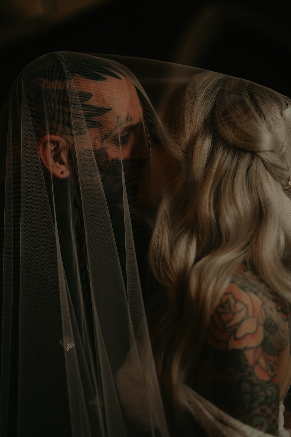 A tattooed wedding couple covered by a large wedding veil at Lympne Castle in Kent.