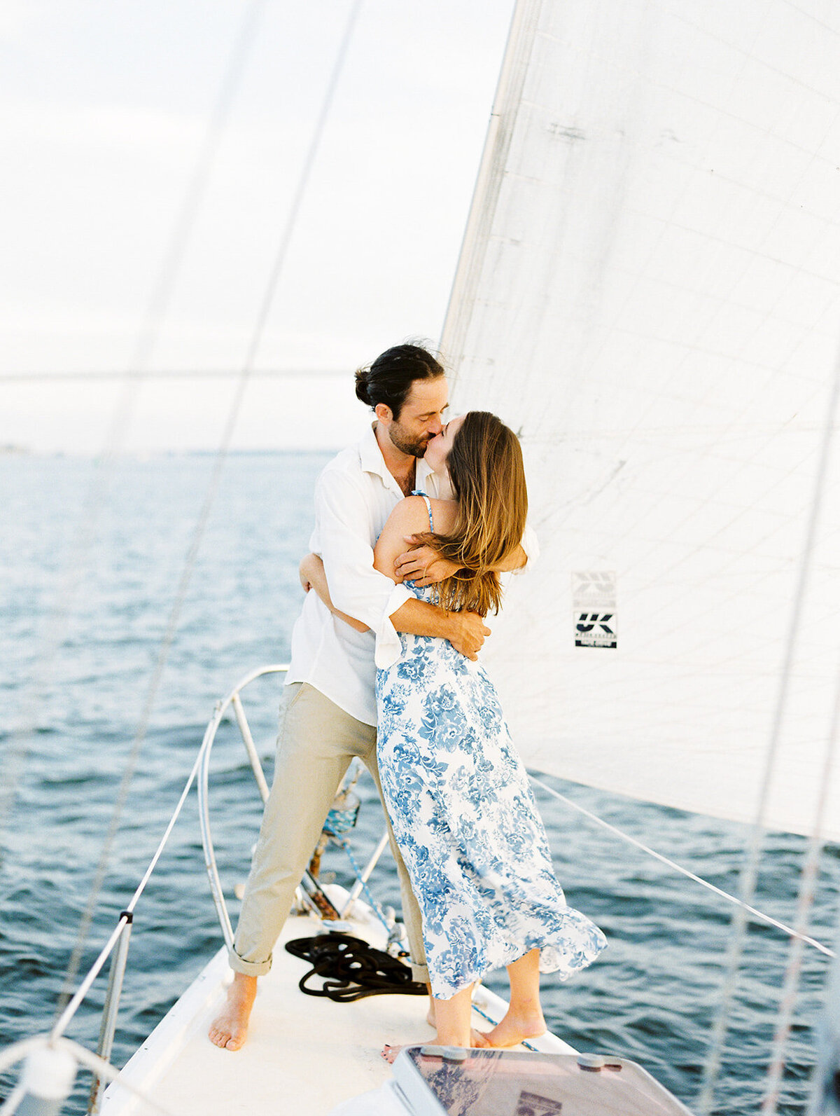 Charleston harbor spring sunset engagement session. Girl in white and blue dress. Guy in khakis, no shoes, and white button up shirt. Charleston film wedding photographer.