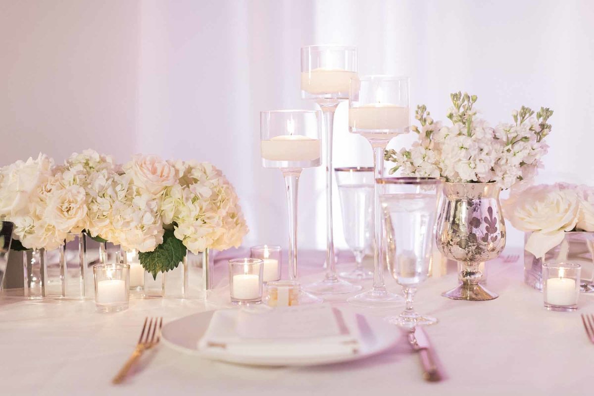 Soft and romantic all white reception with hydrangea, roses and stock, plus an abundance of candles!