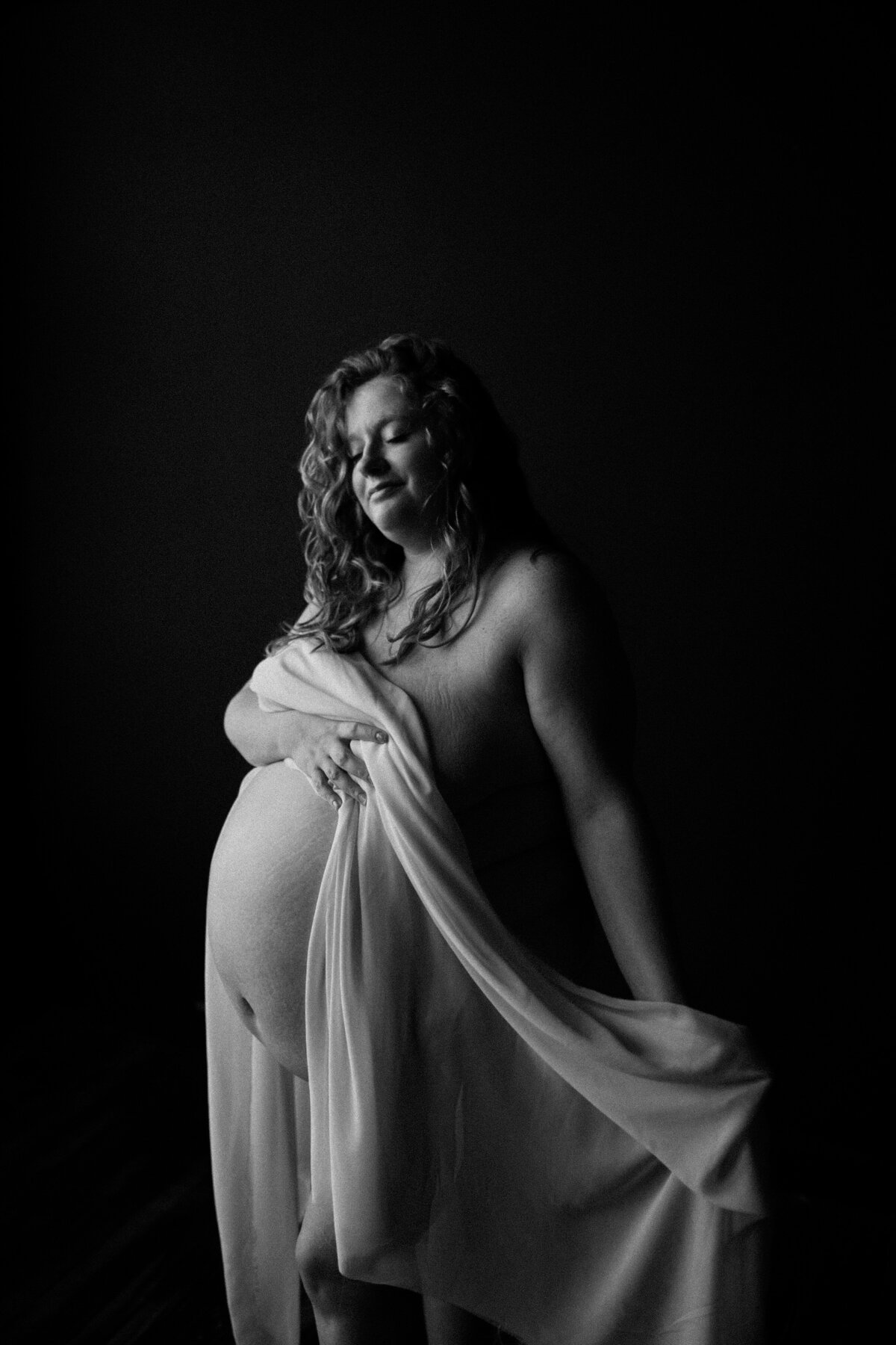 black and white image pregnant mother posing with sheet