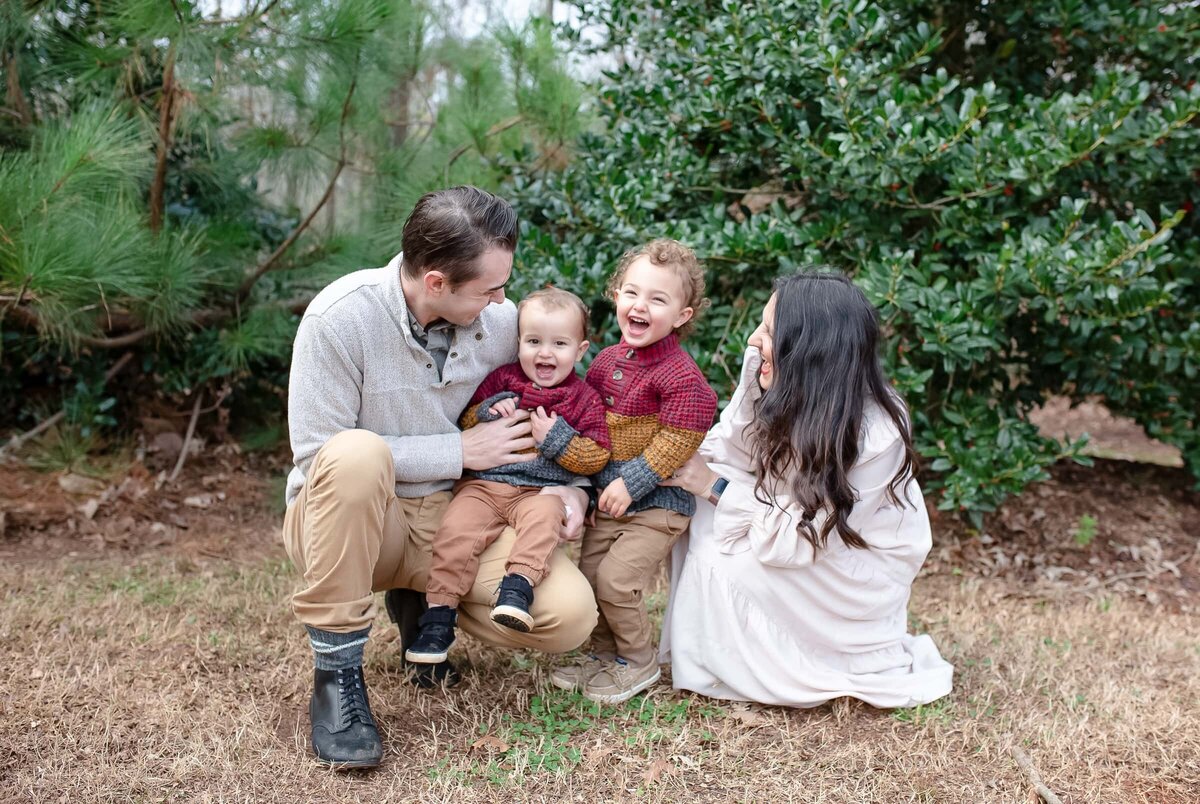 winter family photos in wake forest, NC.  Mom and dad tickling their toddler sons.