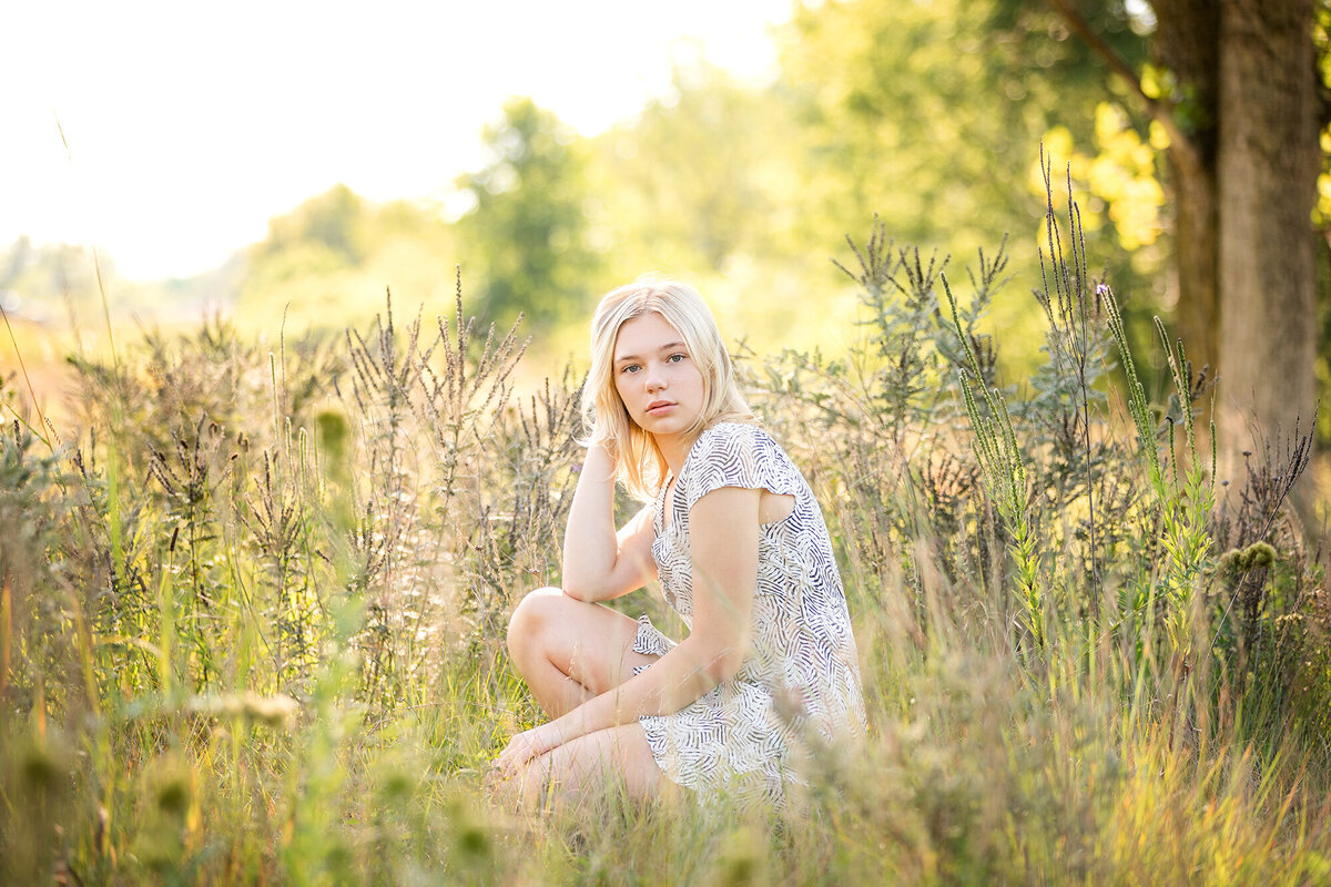 Girl poses in wildflowers during her senior pictures.