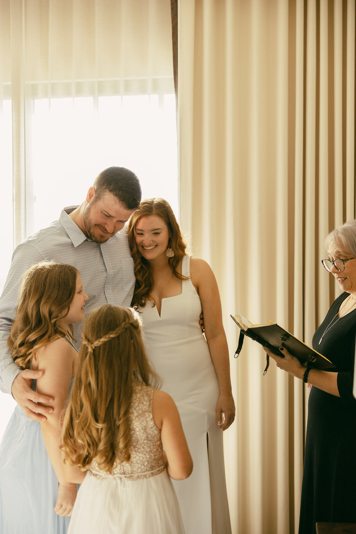 A wedding couple standing together with two girls in front of an officiant.