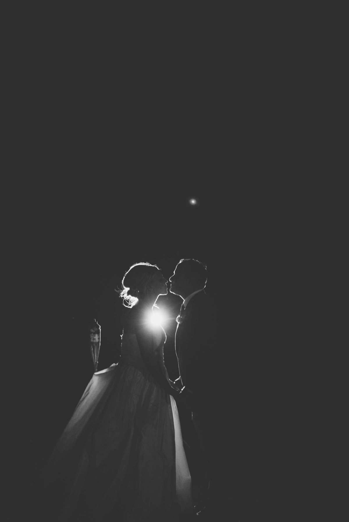 Bride and groom kissing with light shining from behind at Huntington Crescent Club