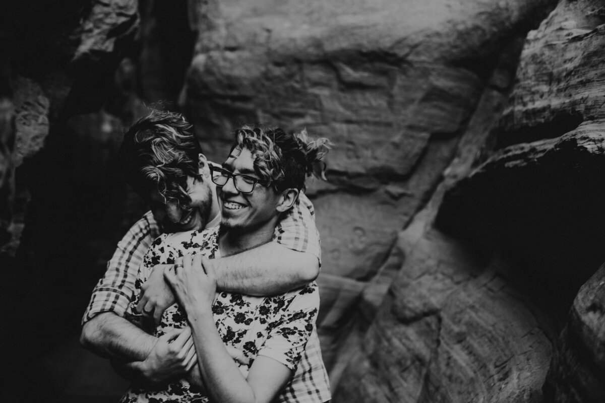 same sex couple holding each other in canyon