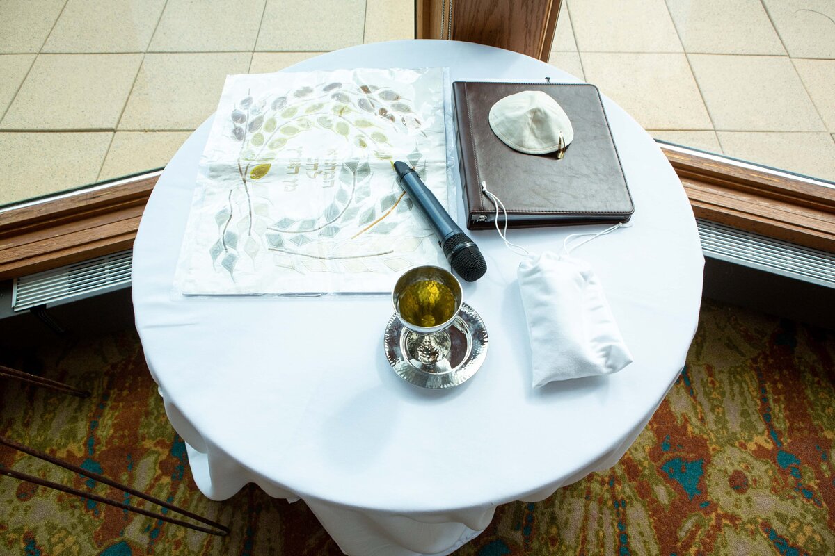 A table set with a crystal ball, white tablecloth, journal, pen, and a face mask, positioned near a window at Park Farm Winery.