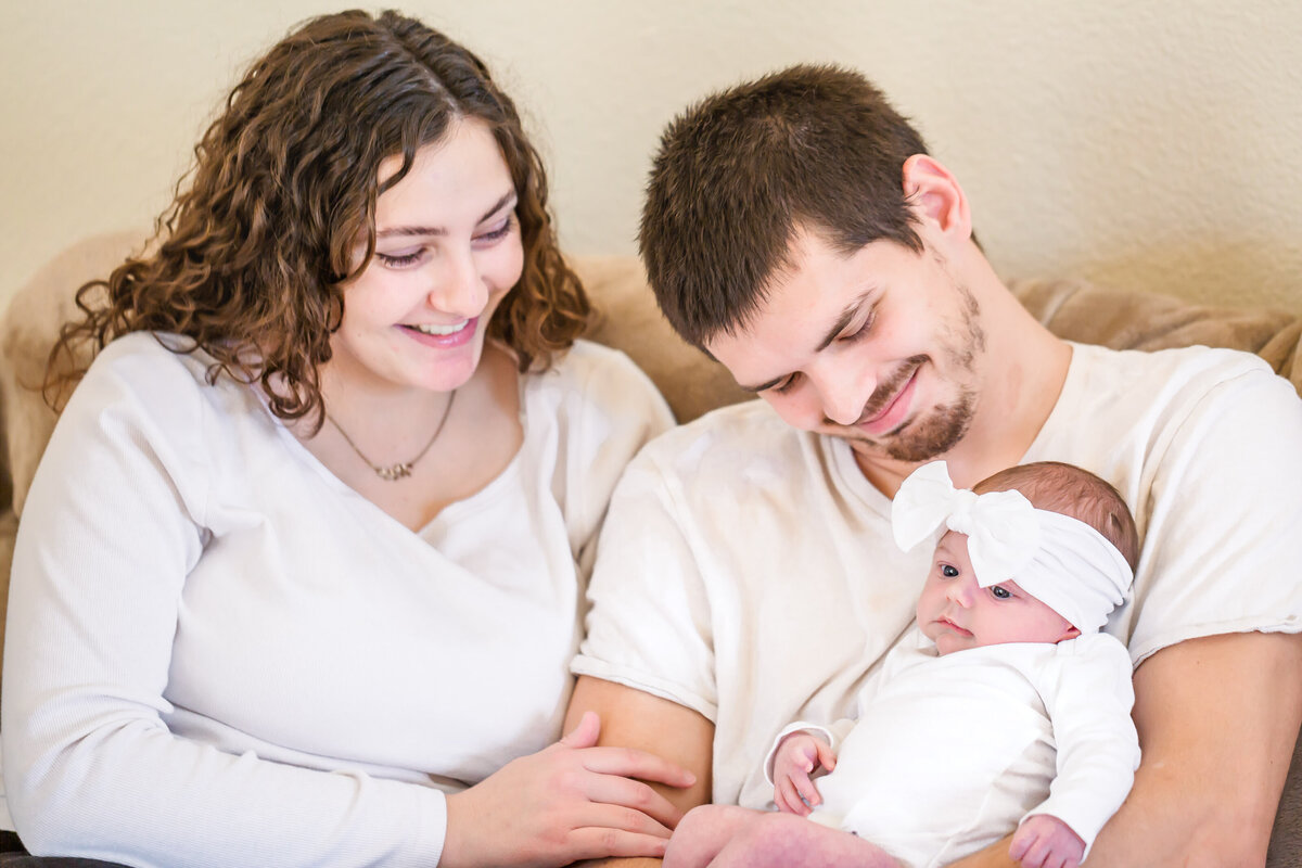 New parents sitting on the couch with their newborn baby girl
