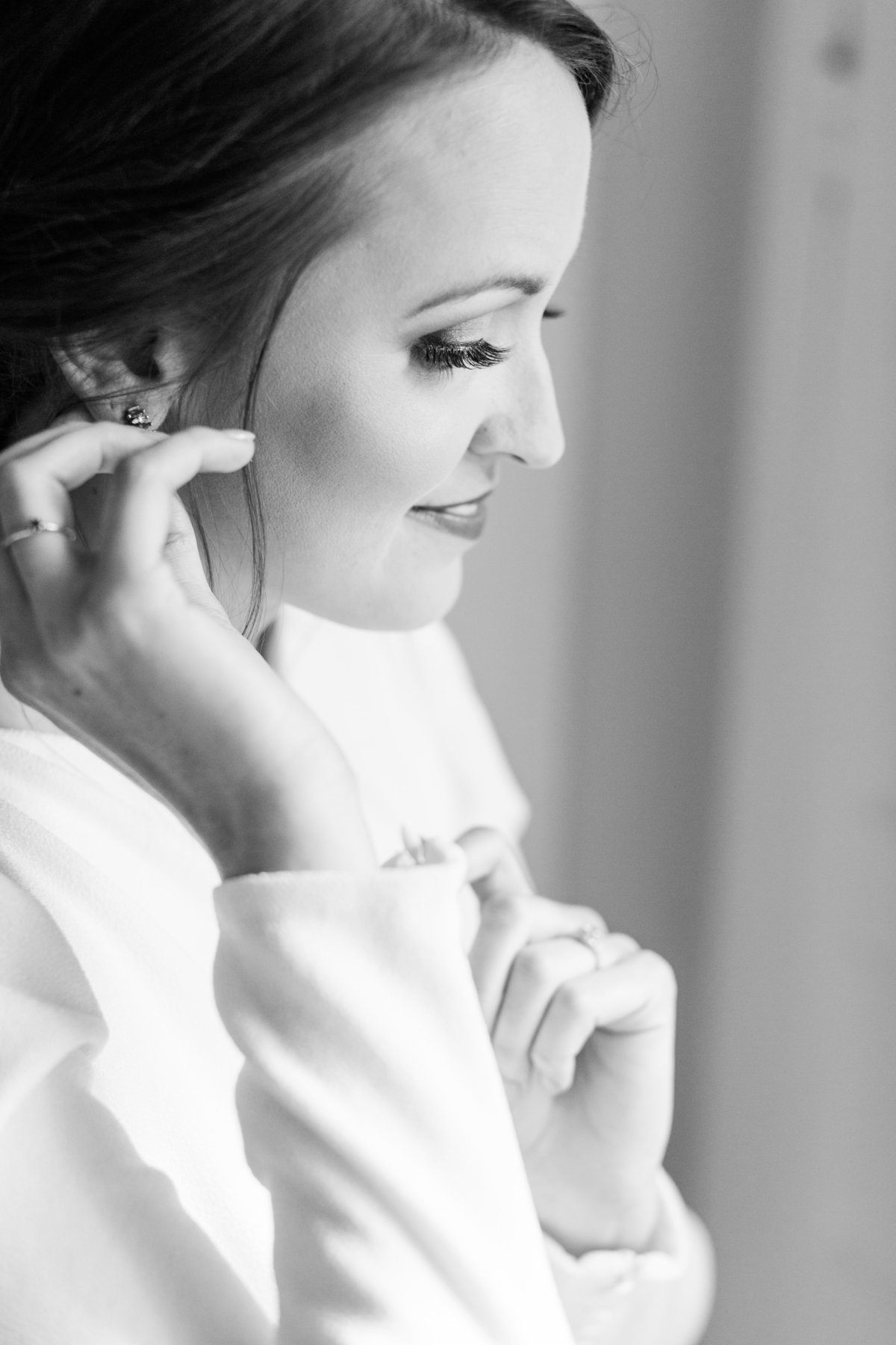bride getting ready; putting on earrings