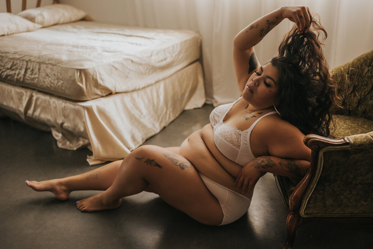plus size woman wearing white lingerie posing on a chair in a vancouver boudoir studio