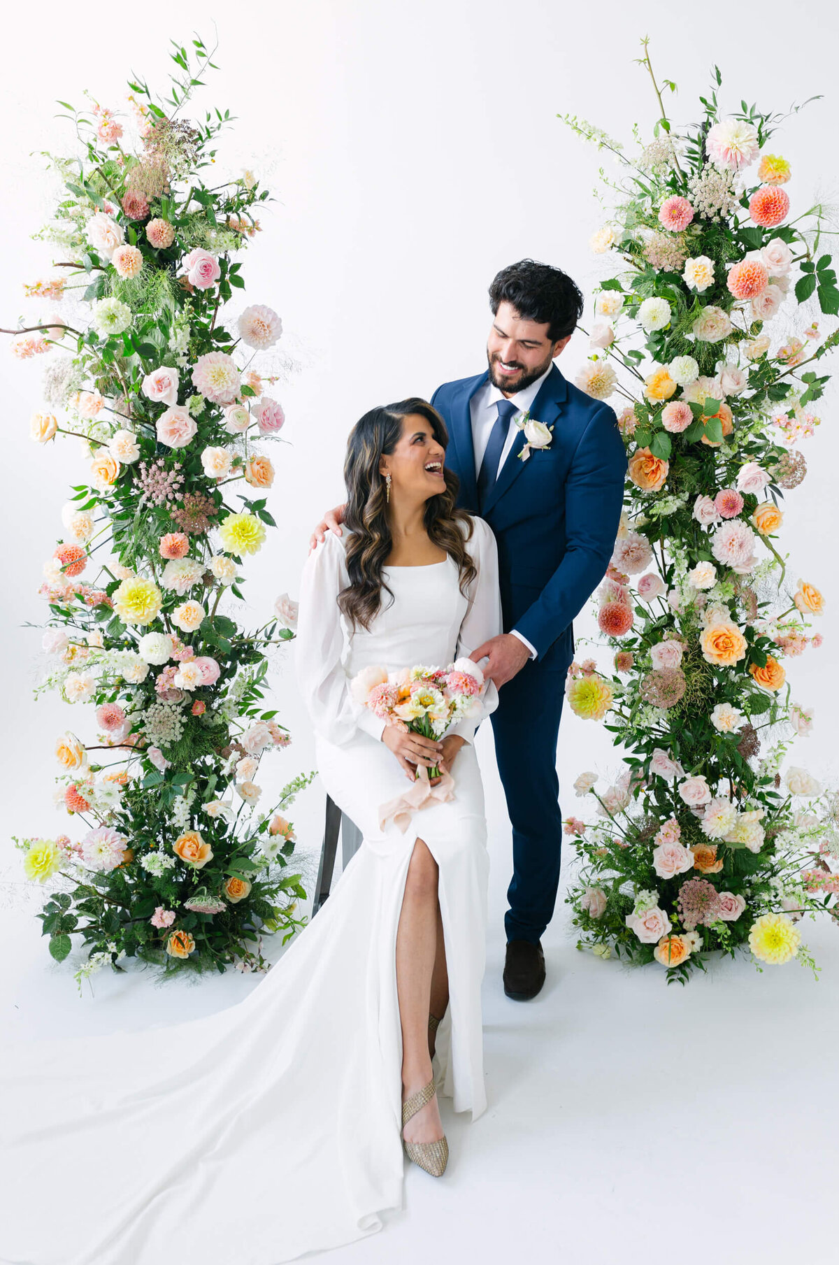 couple standing in flower arch at wedding