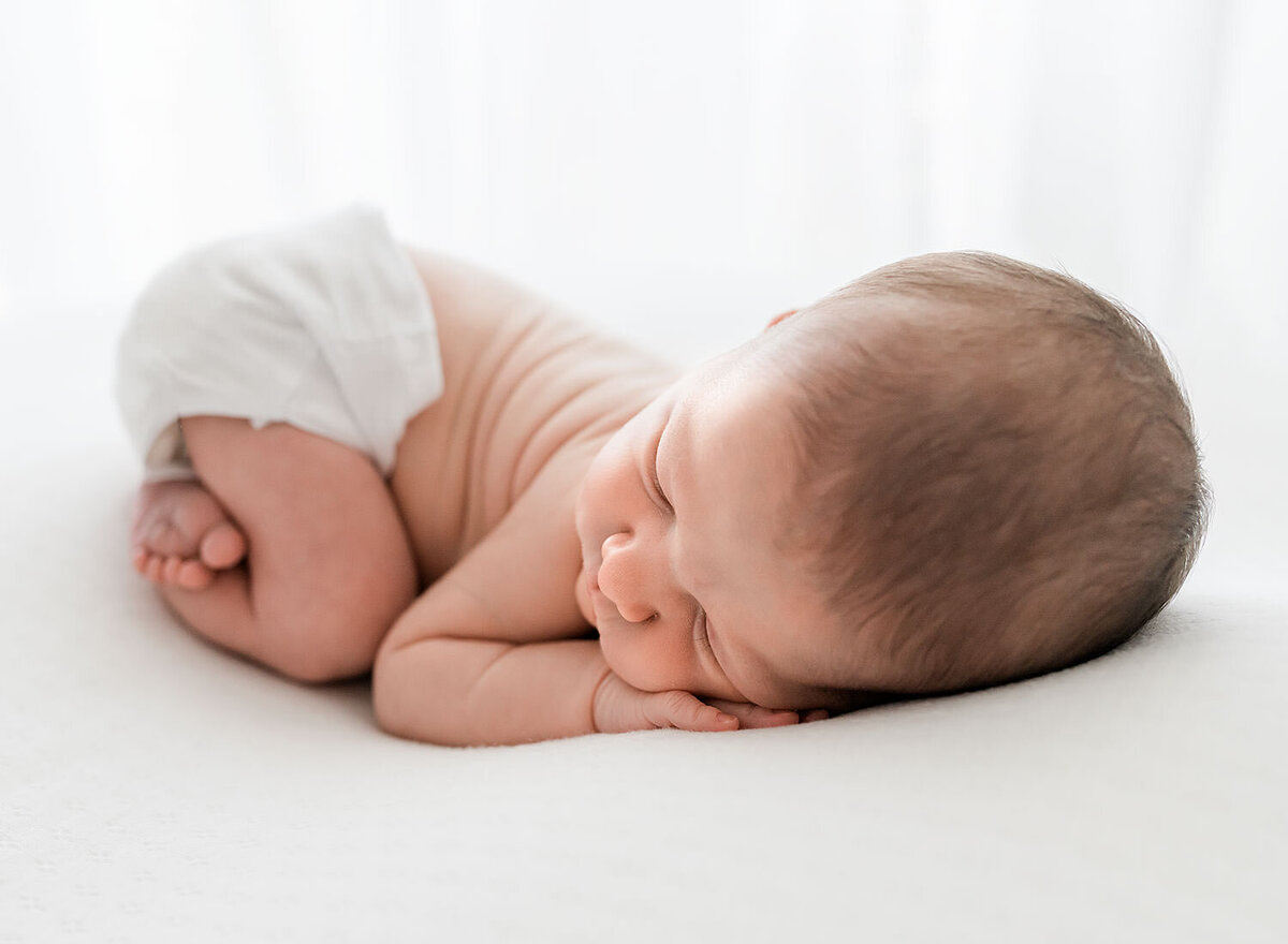 A newborn baby captured by Destin FL family photographers as it peacefully rests on a white blanket.
