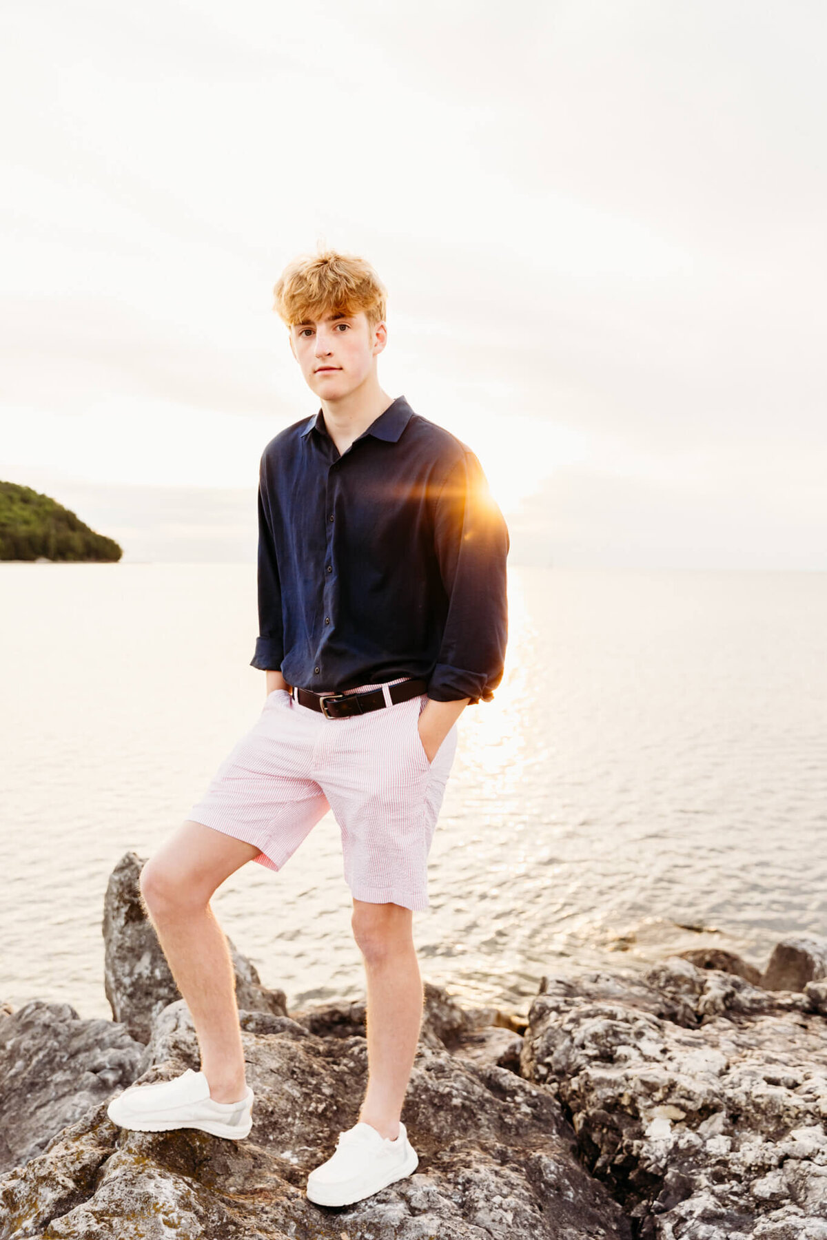 senior photography session with a boy leaning against a post on a fishing dock