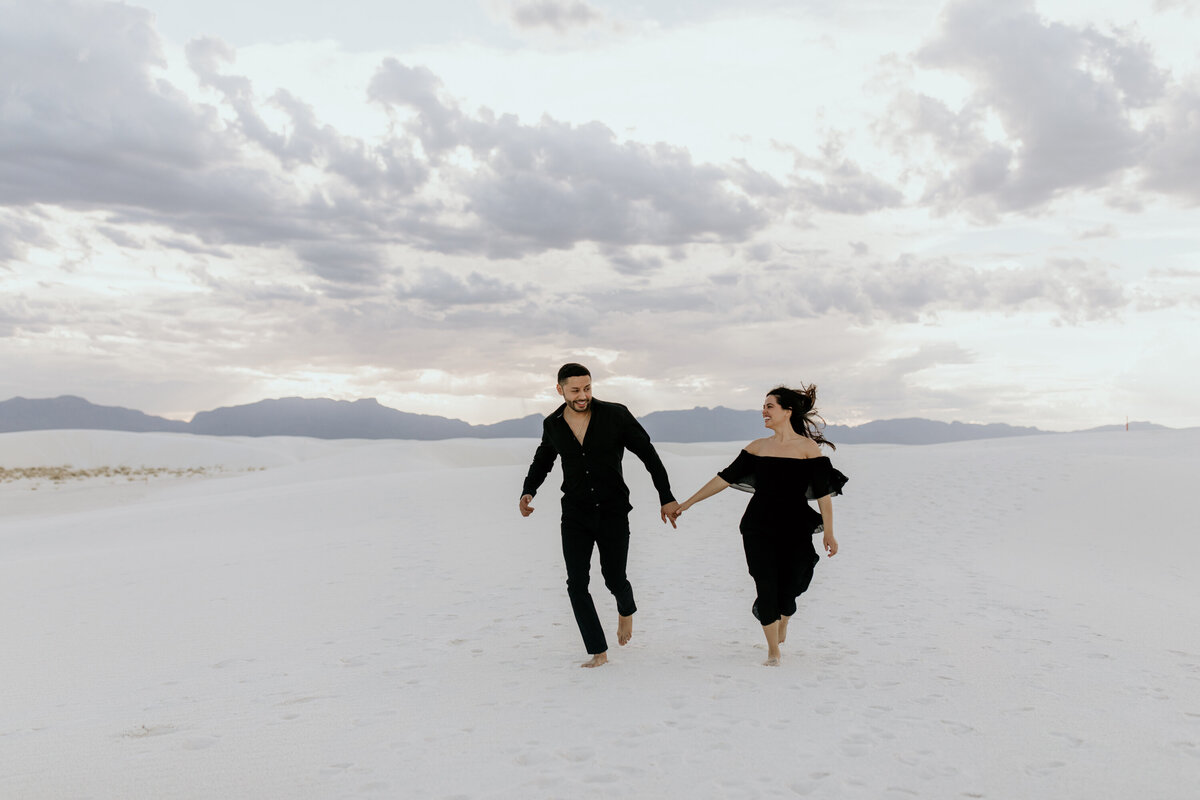 man and woman holding hands running together at white sands NP