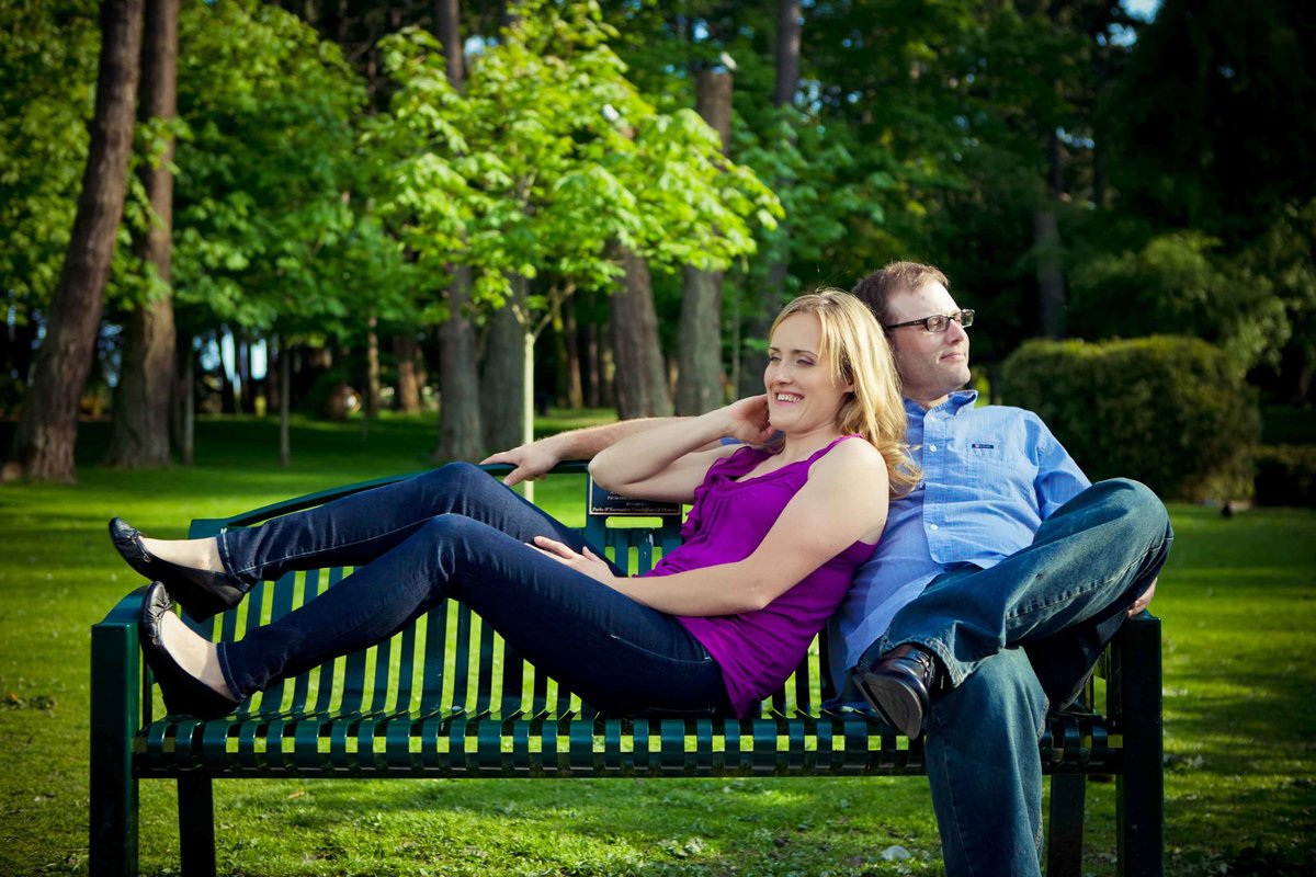 Couple relax on bench in Beacon Hill Park Victoria