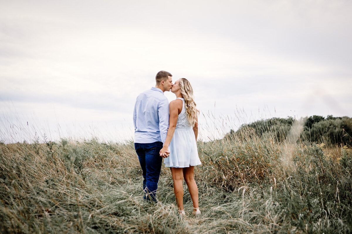 Engaged couple kissing in field in Buffalo Outer Harbour, New York