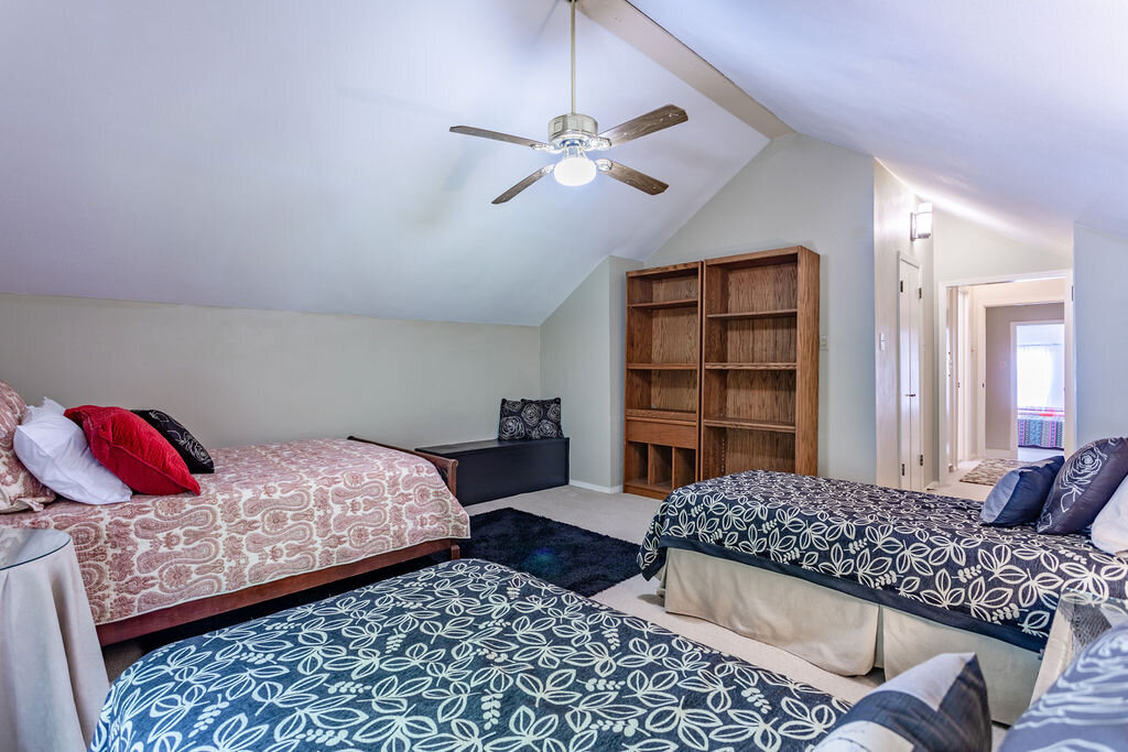 Bedroom with three beds and comfortable bedding in this 5-bedroom, 4-bathroom vacation rental house for 16+ guests with pool, free wifi, guesthouse and game room just 20 minutes away from downtown Waco, TX.