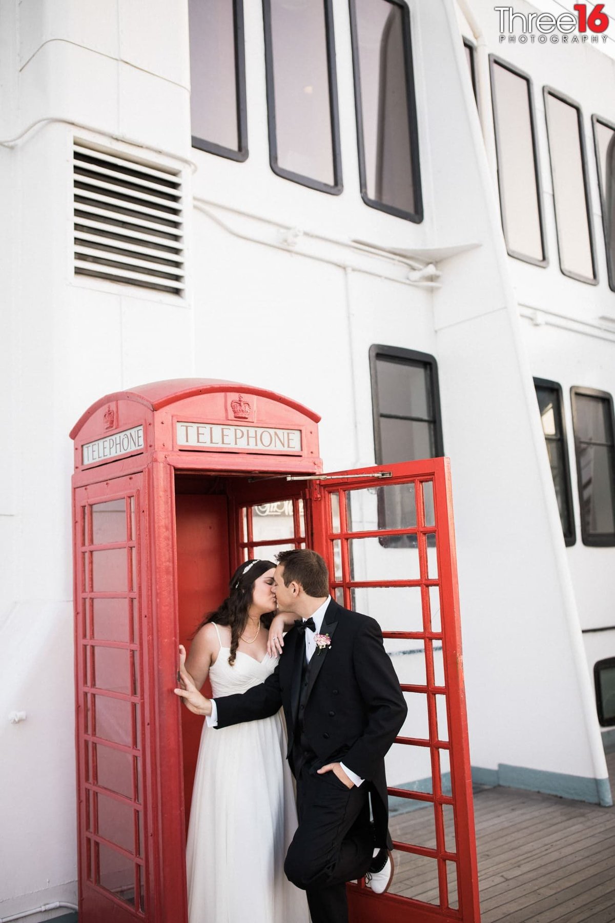 Bride and Groom share a kiss in the entry way to an English-style red phone booth
