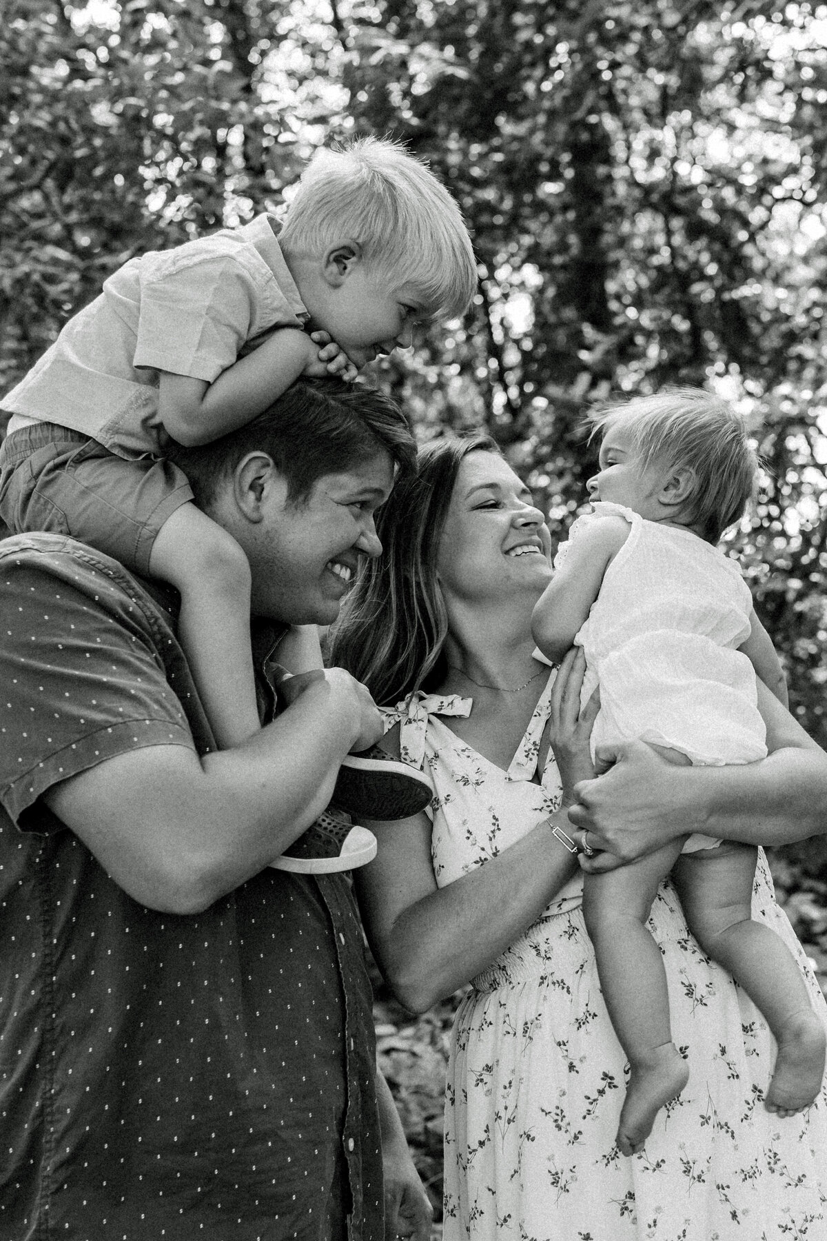 black and white photo of family of four cuddling and laughing