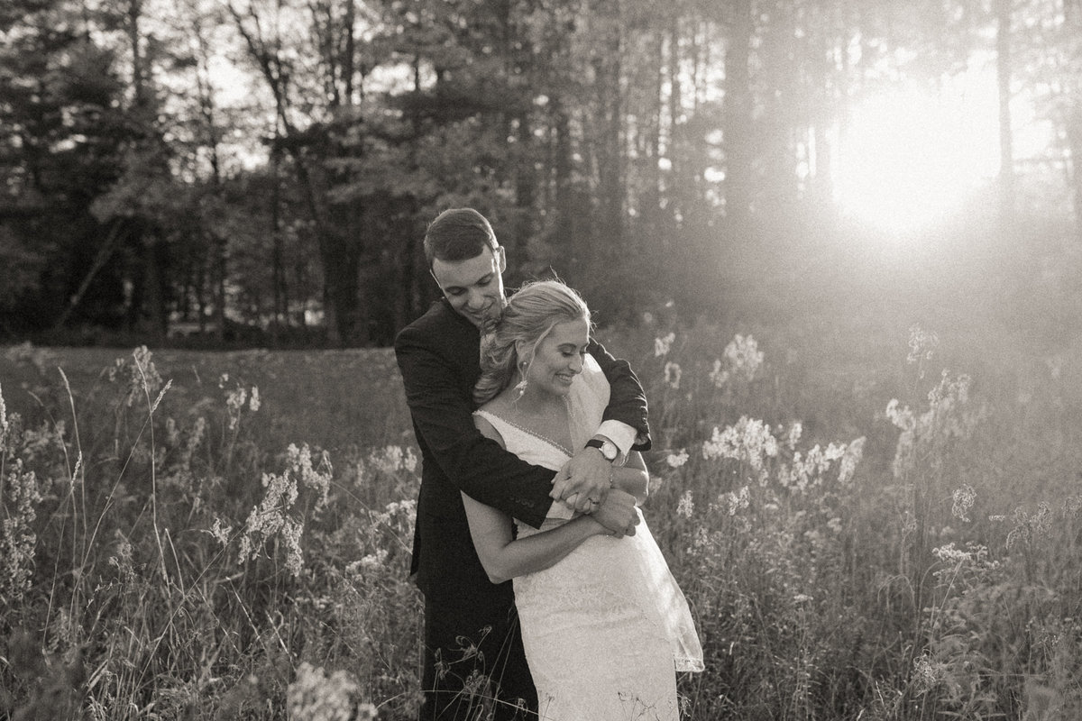 bride and groom dancing in a field in Vermont, with the sunlight beaming behind them