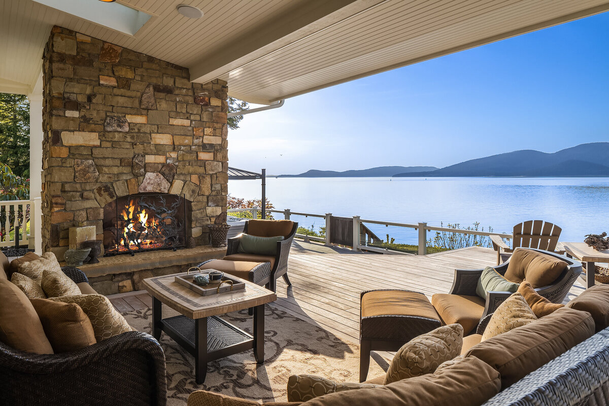 covered deck with fireplace and waterfront view