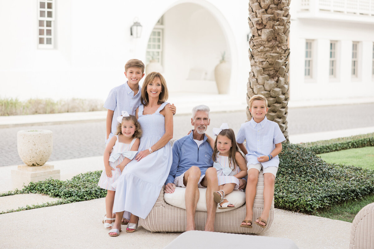 A family sitting on a small bench together smiling