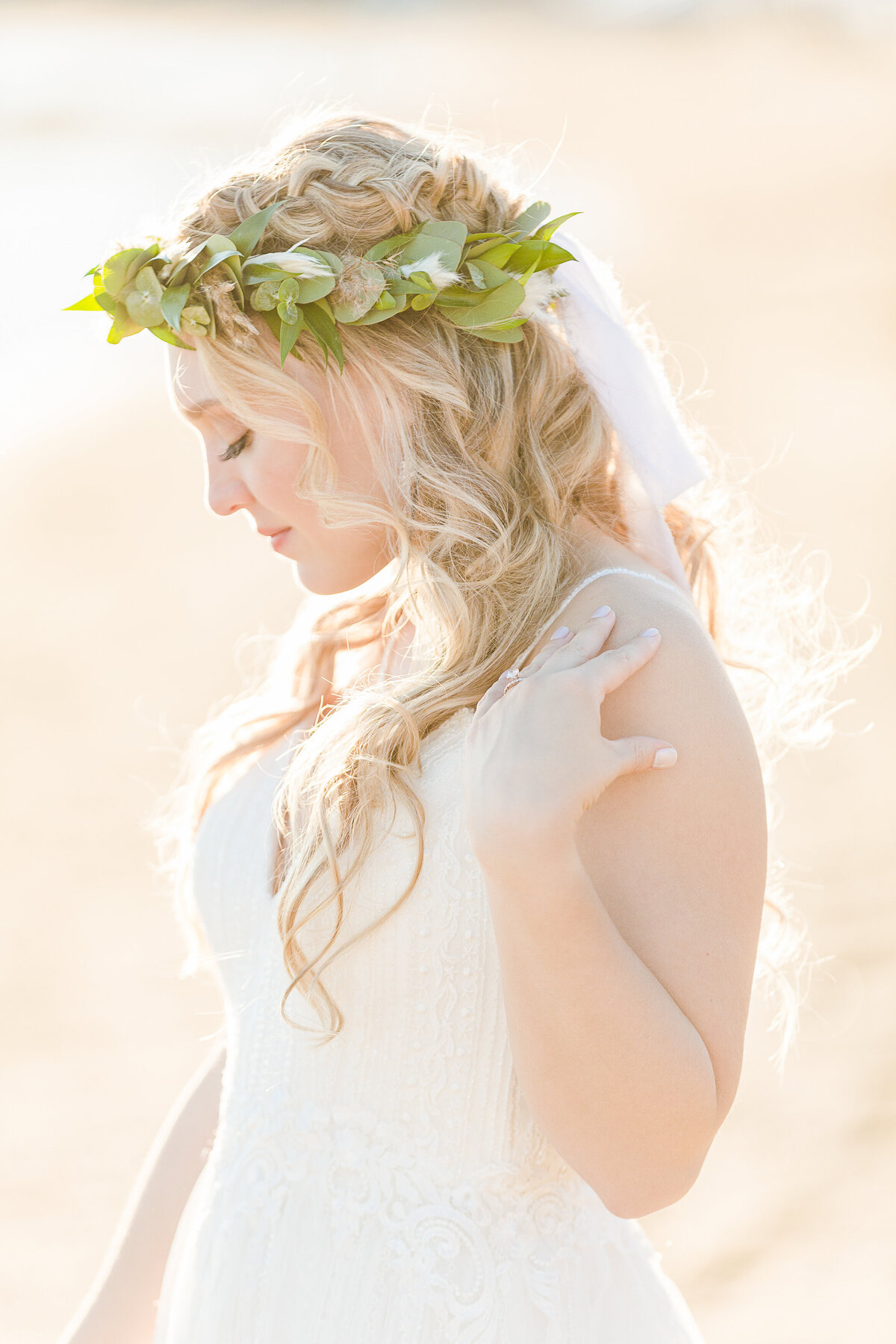 Side profile bridal portrait captured at golden hour. She is looking down and touching her shoulder. Captured at the shoreline of the Madison Beach Hotel in Connecticut by Lia Rose Weddings.