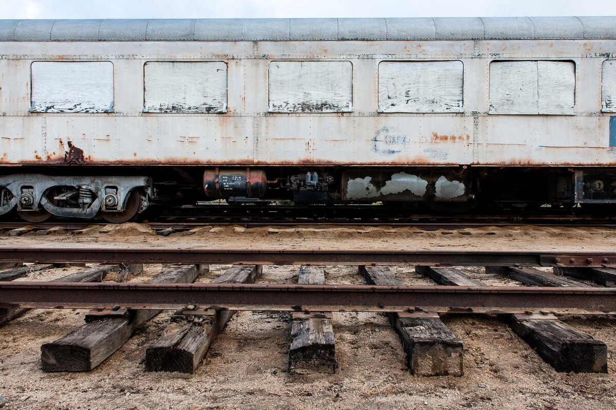 Profile of a white passenger train that is rusting away.