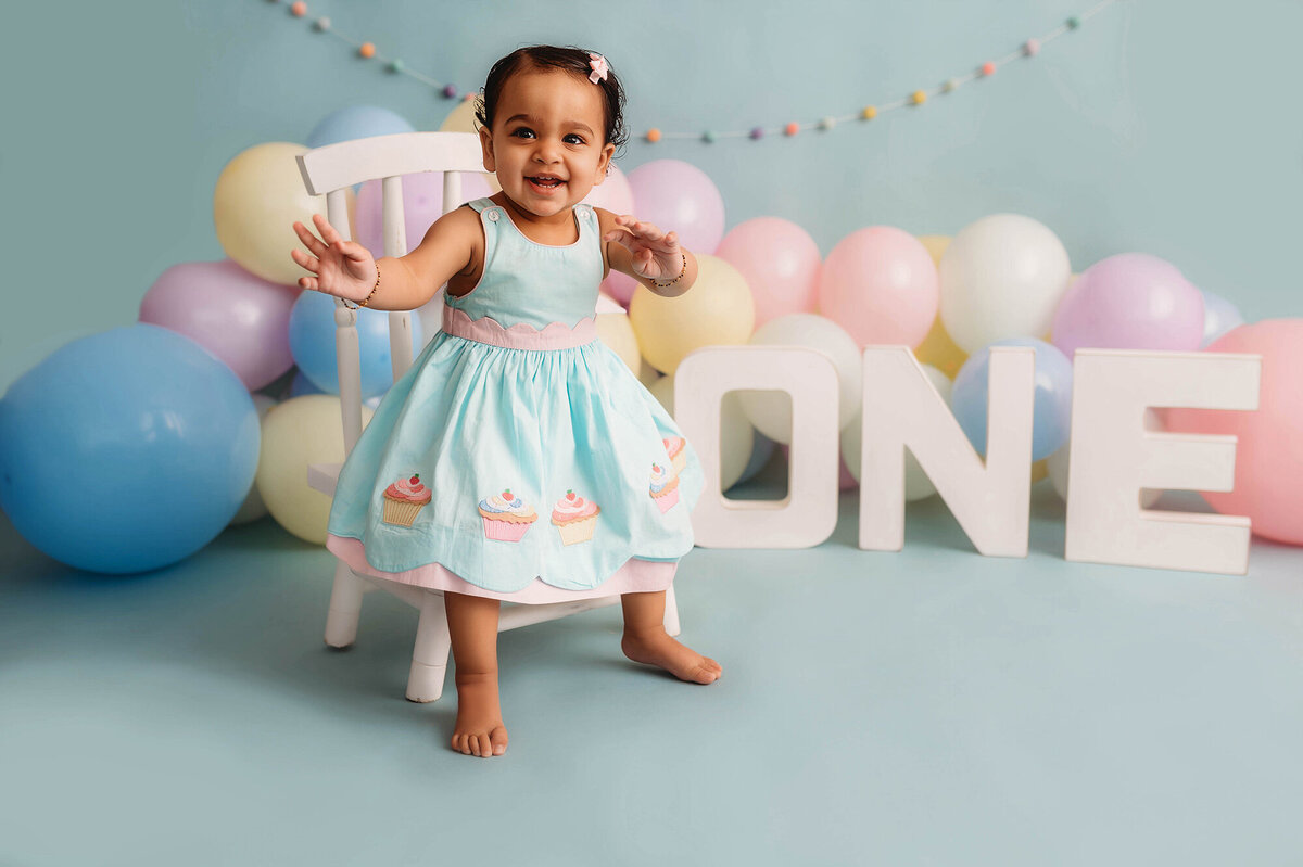 Little girl poses for first birthday cake smash photos in Asheville, NC.