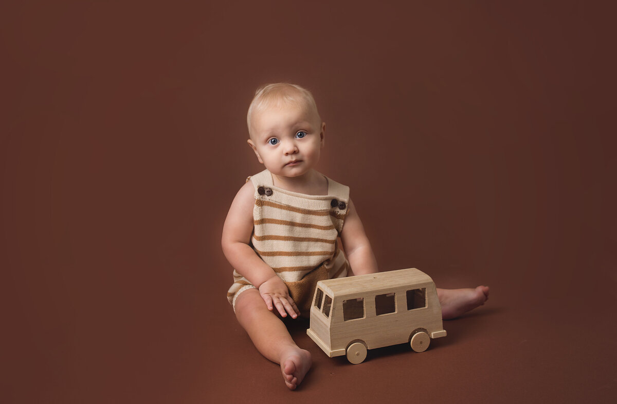 Baby boy wearing tan romper during cake smash photoshoot in Franklin, Tennessee Photography studio