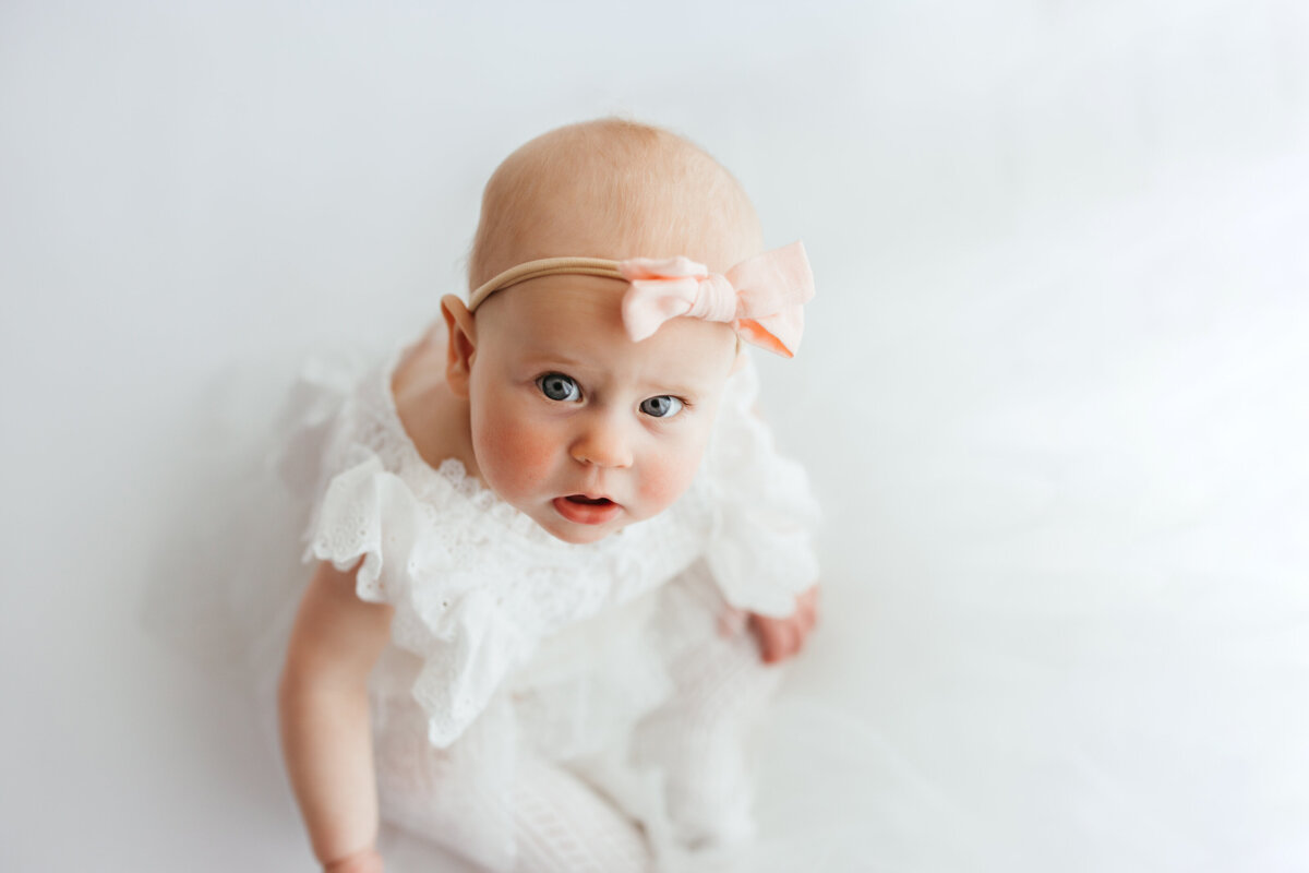 baby girl milesone session in studio wearing a white romper and boy