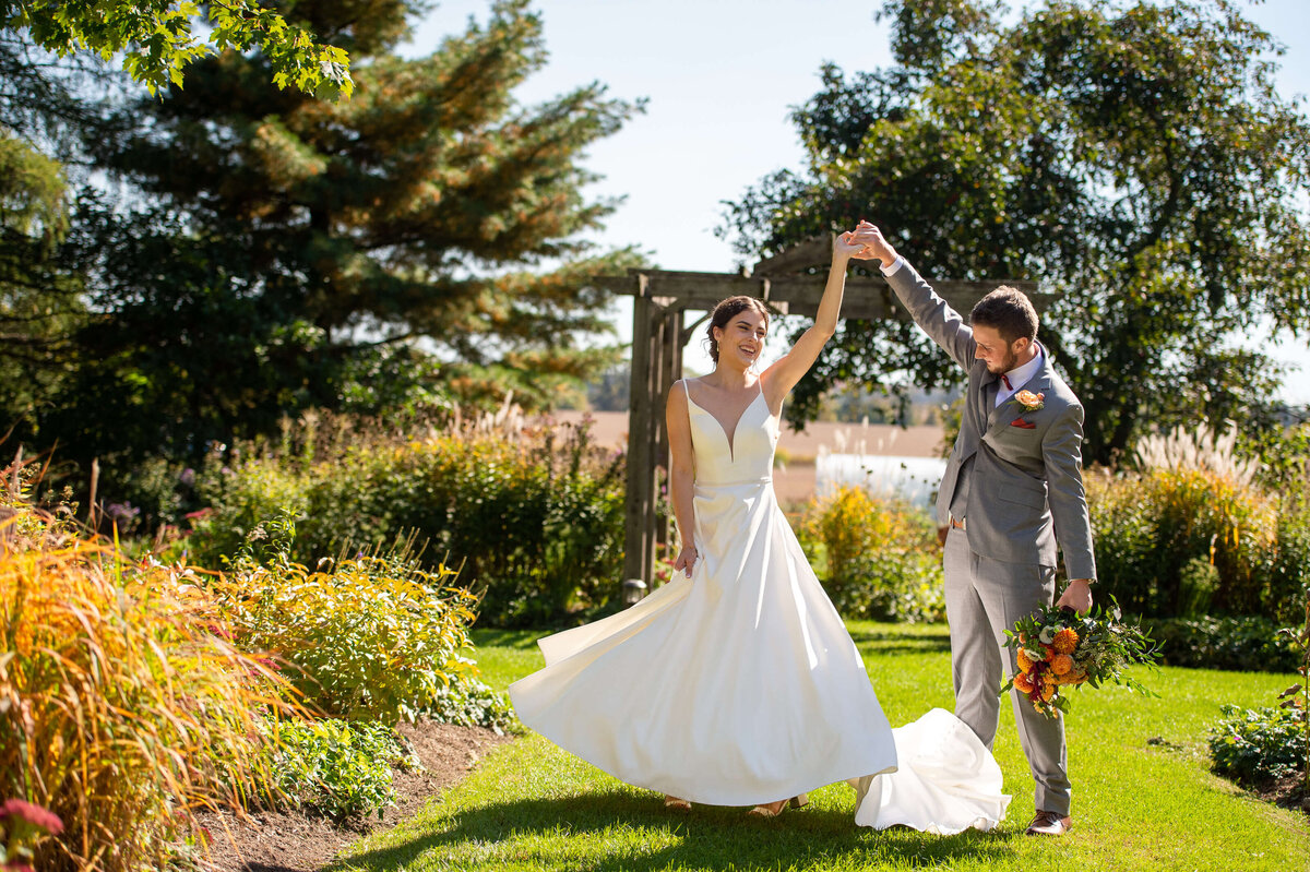 a bride and groom twirl during their Ottawa wedding taken outside in the gardens of Strathmere wedding venue