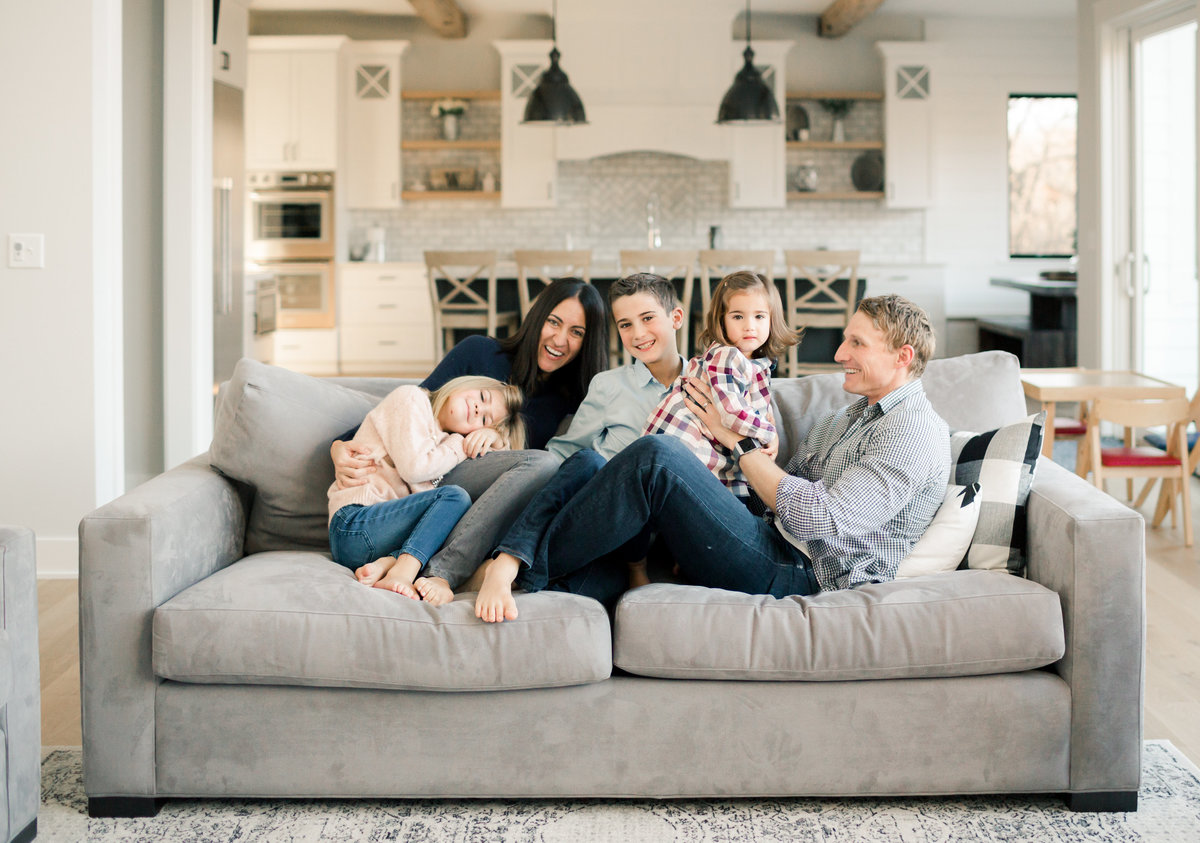 family of five cuddles on couch in new home build rochester minnesota