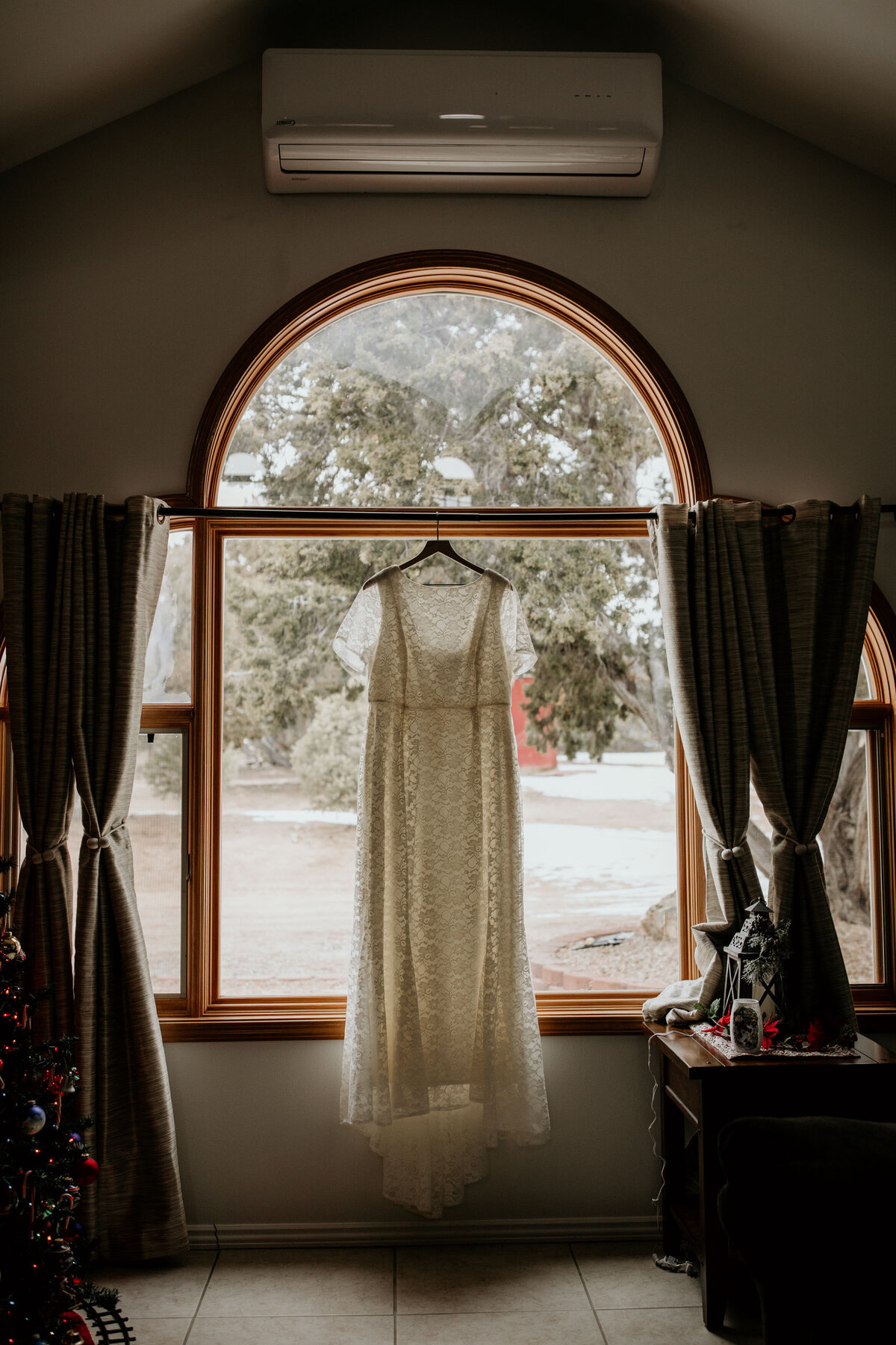 lace wedding dress hanging in front of window