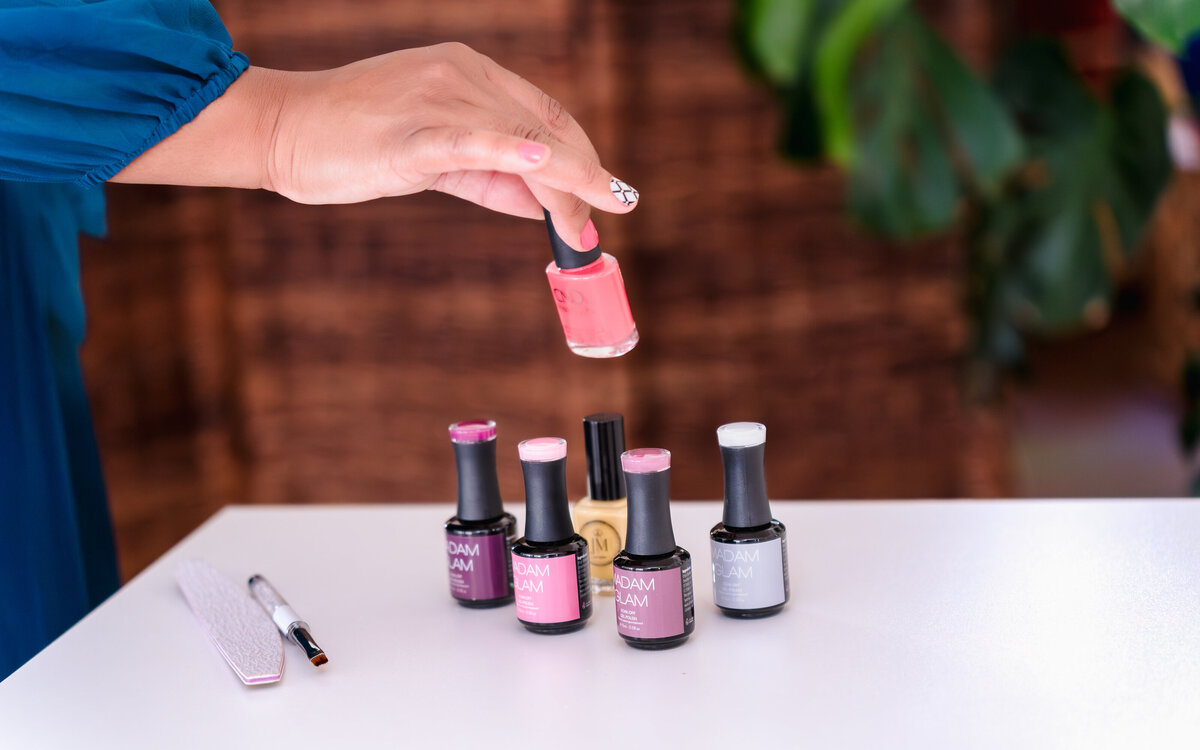 brand photo of a woman holding a nail polish and showcasing the tools of the nail saloon