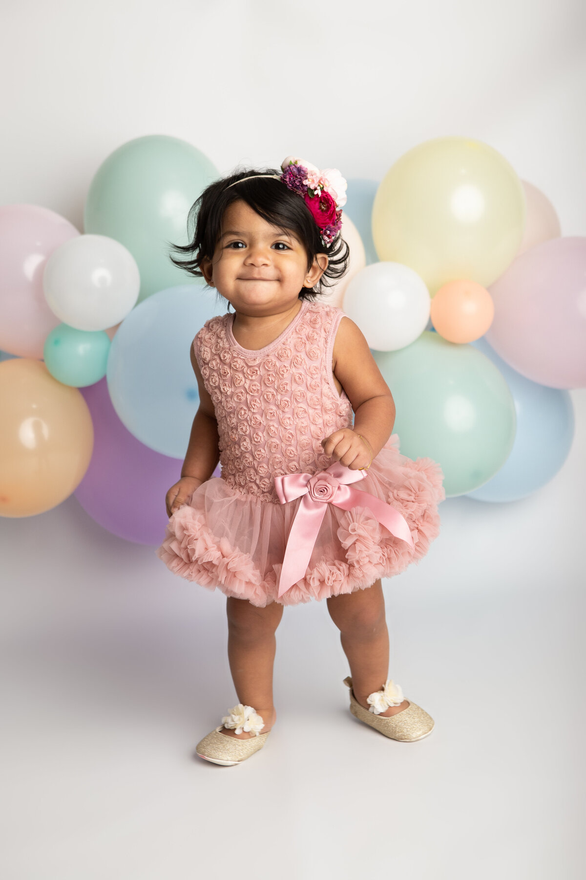 Birthday baby girl with a rainbow balloon garland