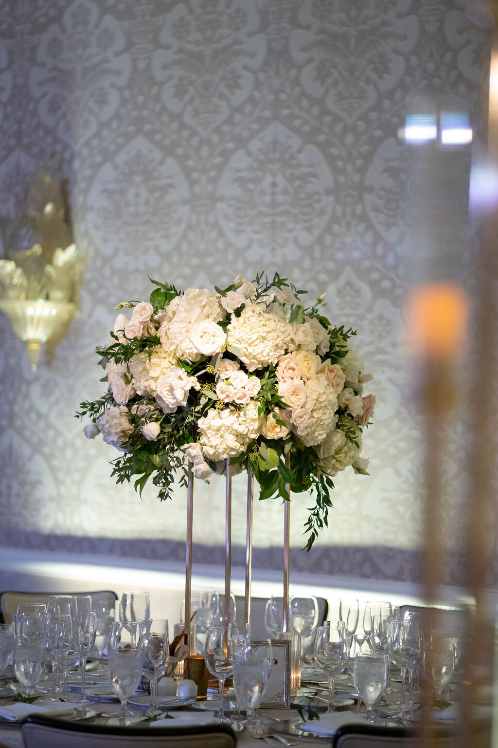 white and green centerpiece on gold stand