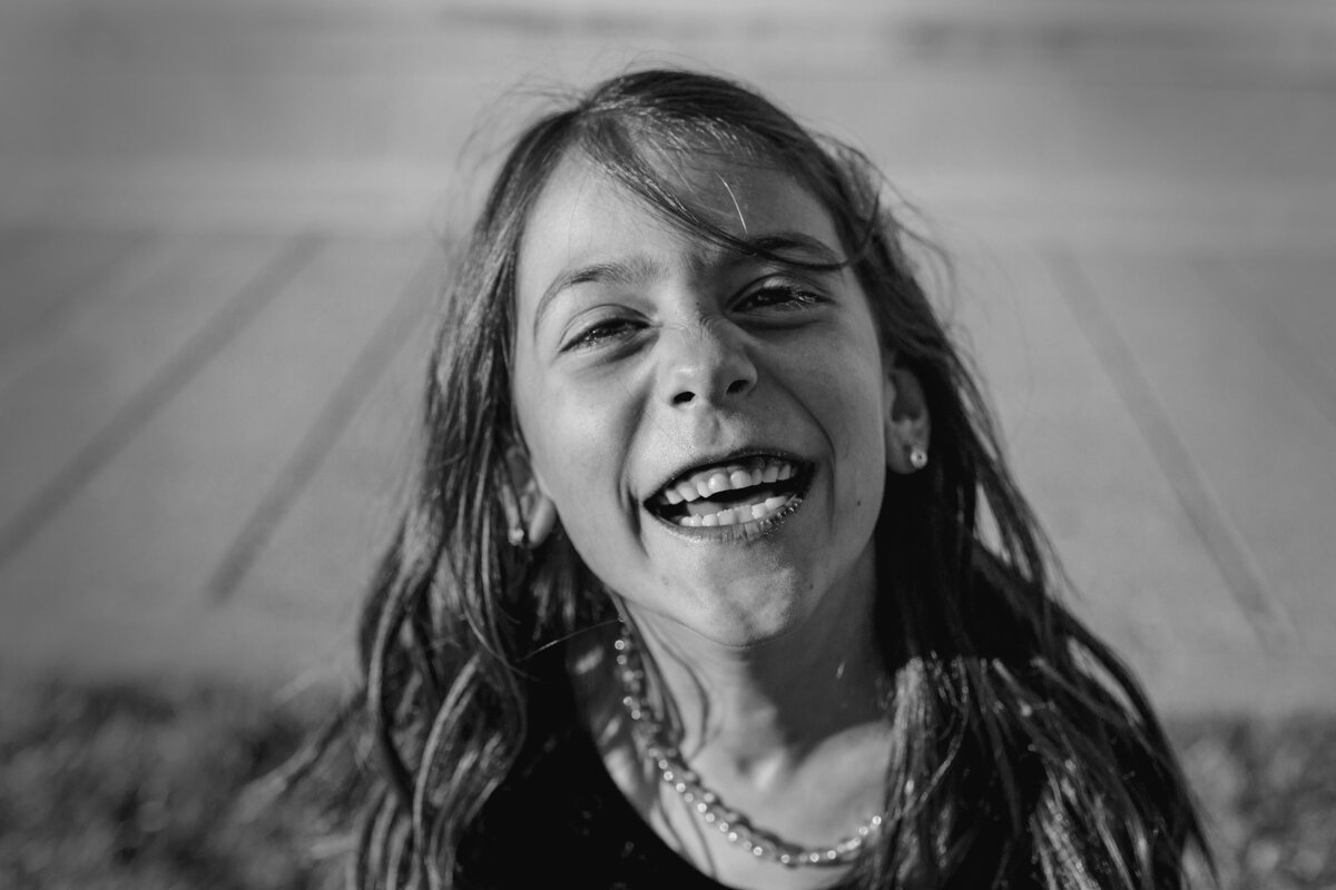 A candid shot of a girl laughing right at the camera, in black-and-white.