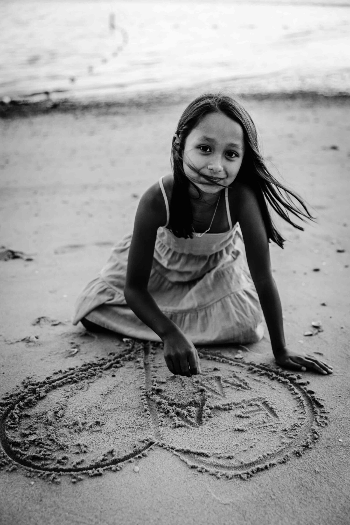 girl drawing heart in sand long island family photography
