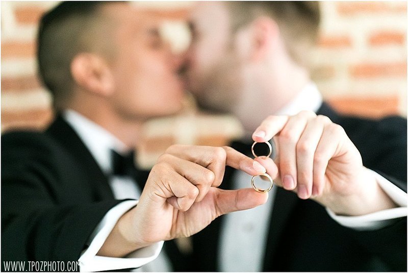 Gay couple with wedding rings kissing