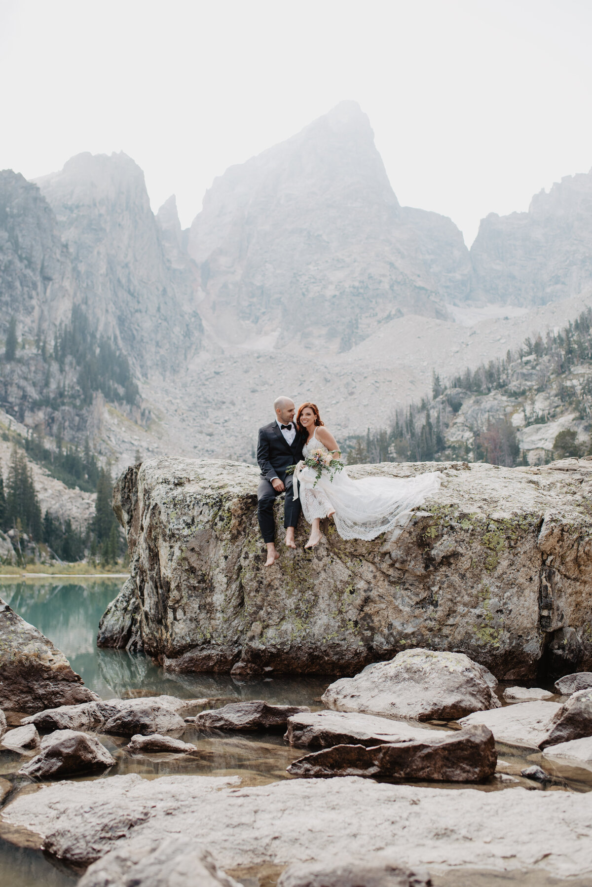 Jackson Hole Photographers capture bride and groom sitting together on rock